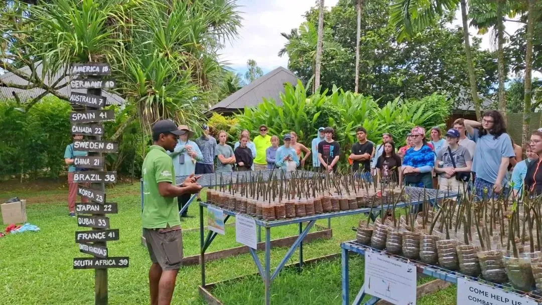 A Fijian man giving instructions on how best to plant mangroves to a group of eager students