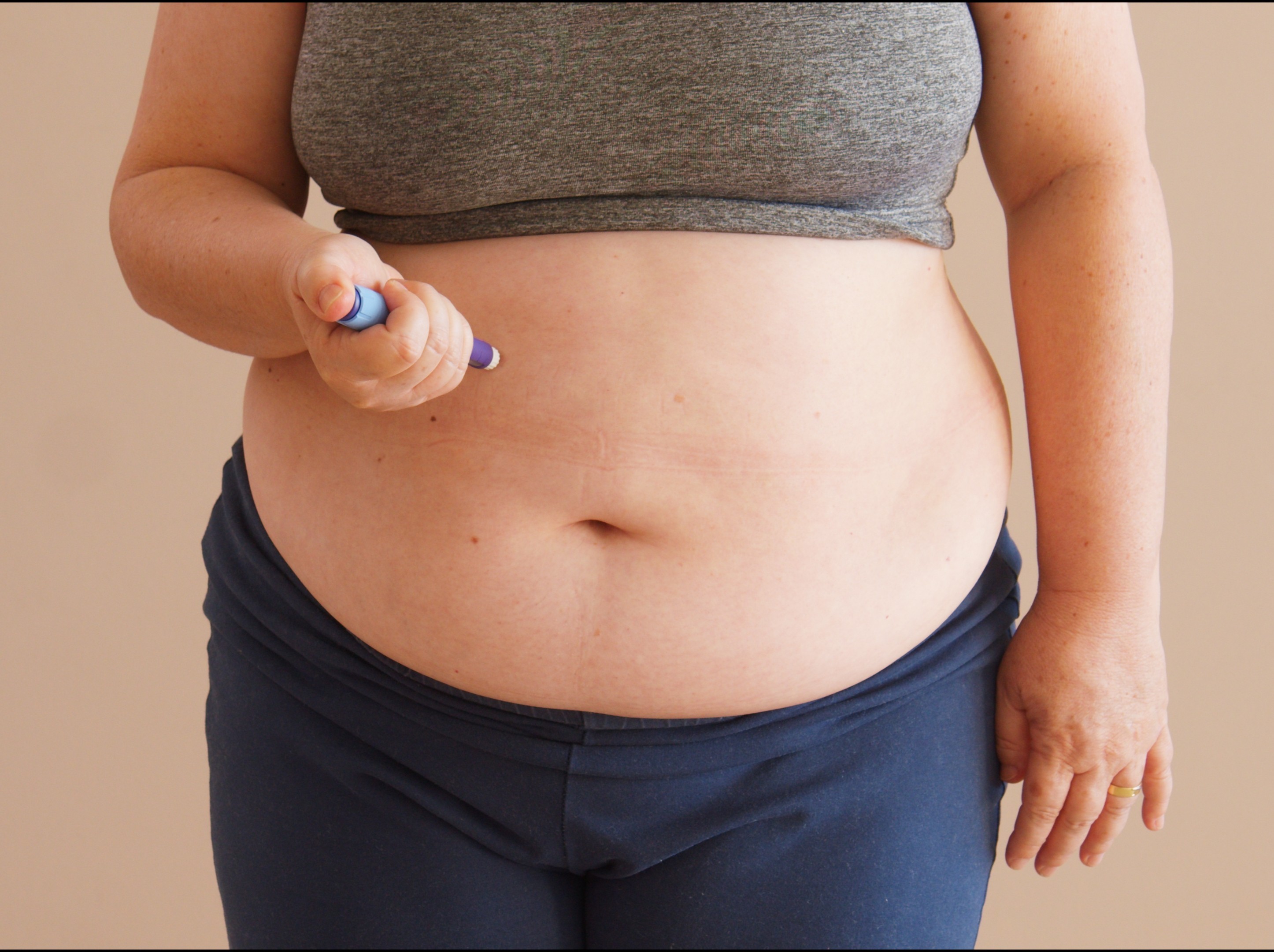 woman standing at home using weight loss shots in her stomach