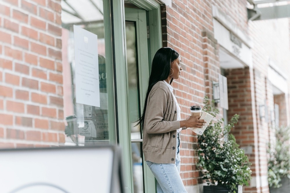 photo d'une jeune femme qui sort d'un café, comme pour montrer un état psychologique après être sortie d'un burn out. Retrouver la lumière avec la VFC et HRV