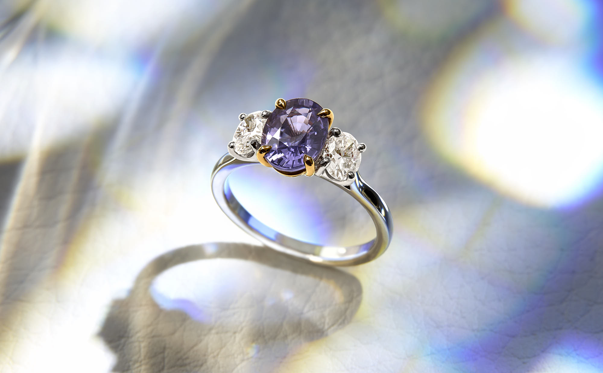 Elegant amethyst and diamond engagement ring on reflective surface.