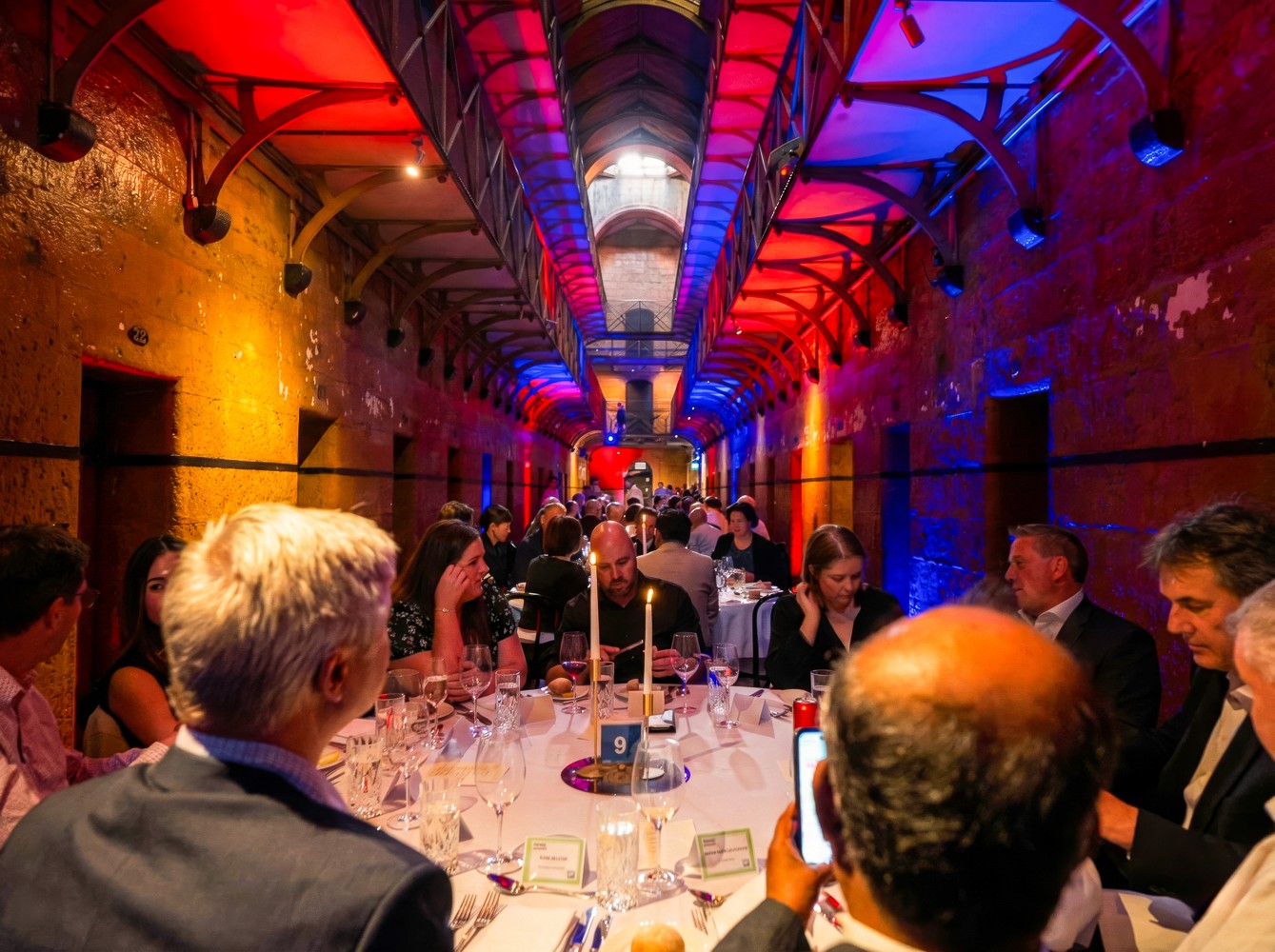 Interior of Old Melbourne Gaol with dining tables and guests 
