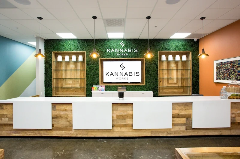 Kannabis Works checkout counter with green tiled wall, wood accents, and lit brand signage.