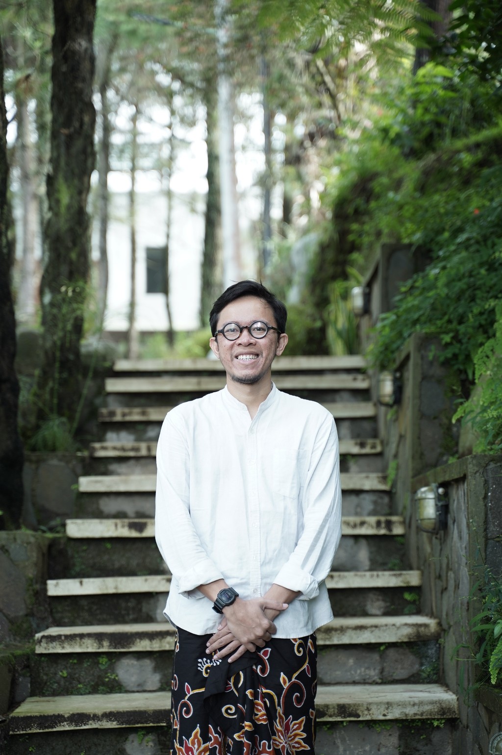 A winding road cuts through rocky terrain, surrounded by patches of green grass and illuminated by sunlight.