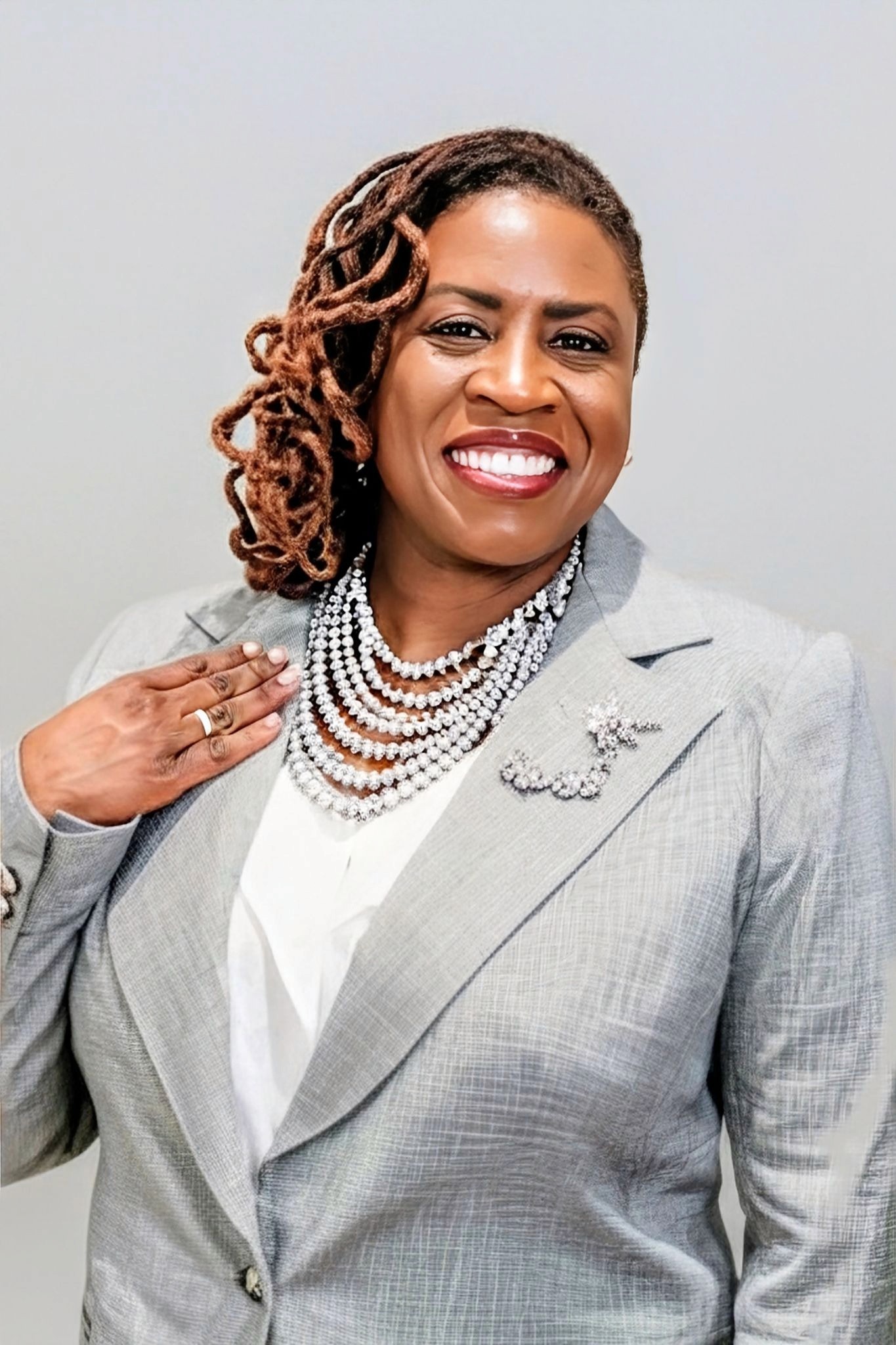 Lynita Mitchell-Blackwell wearing a gray blazer and layered statement necklace in a close-up portrait.