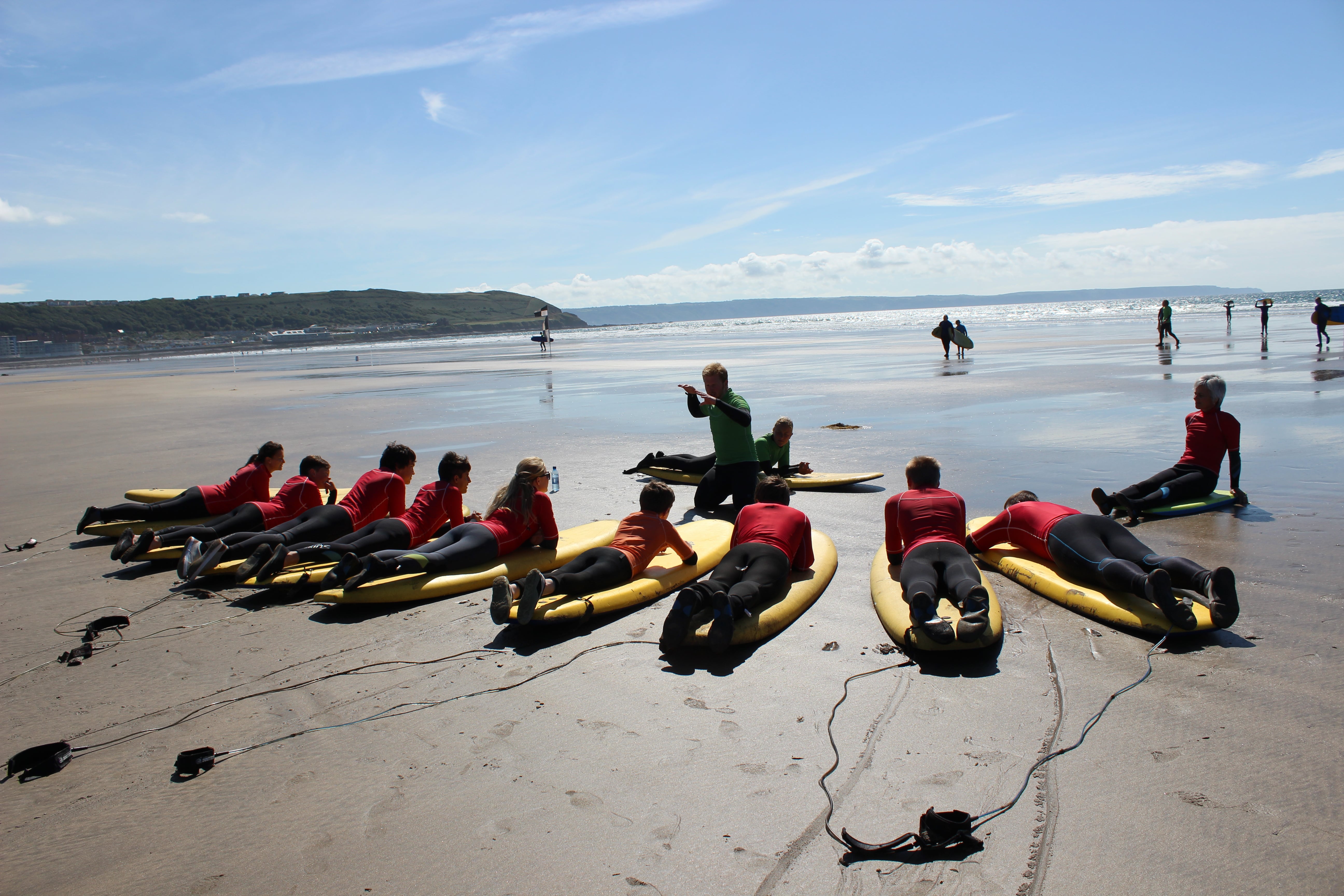 Young people laying down on surfboards at the beach