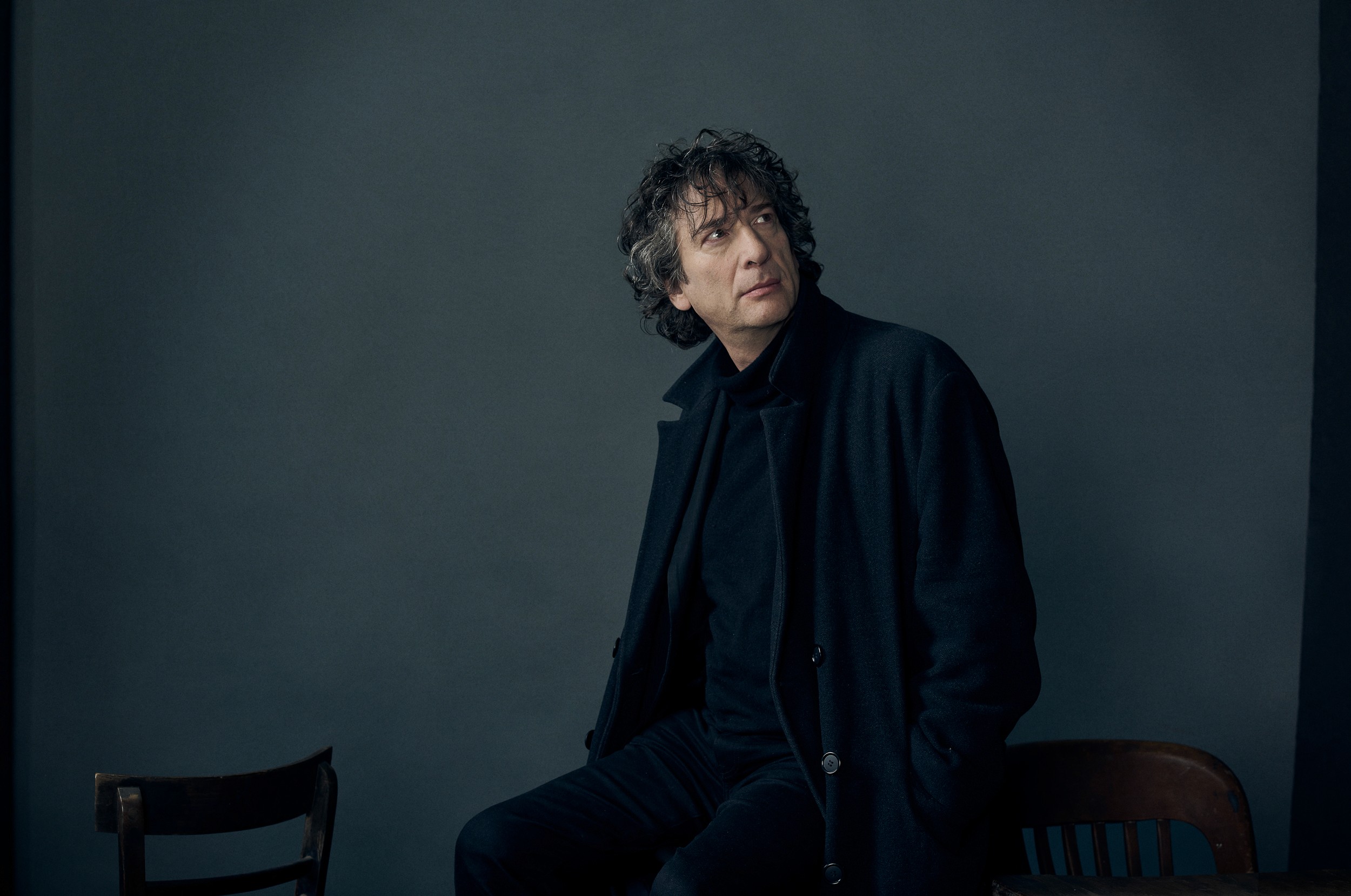 Portrait of writer Neil Gaiman  in front of a textured background.