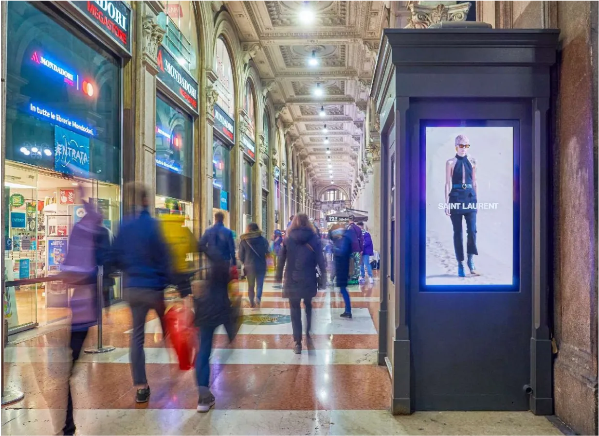 a man walking down a street past a large poster
