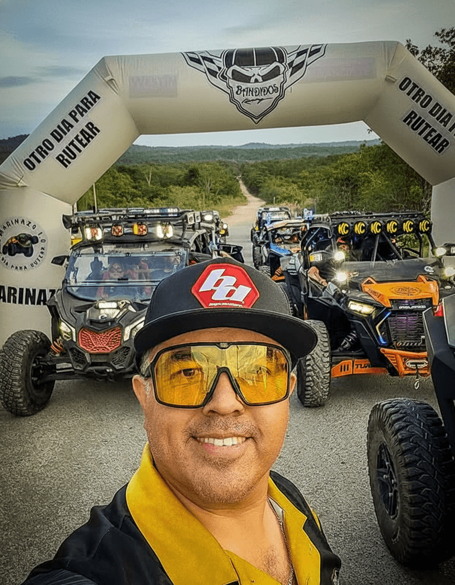 Portrait of a man in a black suit, shirt, and tie with his arms crossed against a gray background.
