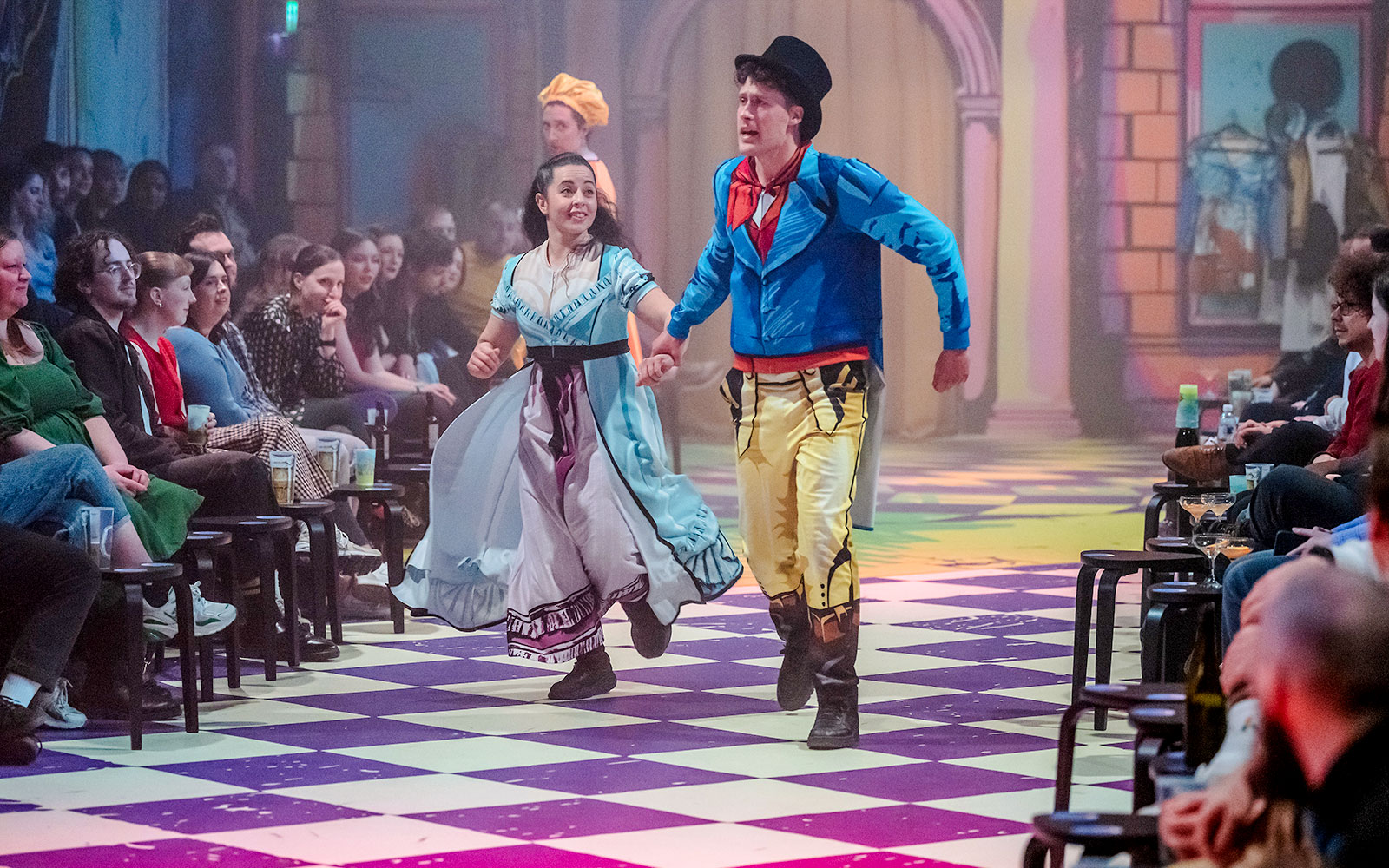 演员们在方格舞台上身着色彩缤纷的服装表演《傲慢与偏见》。