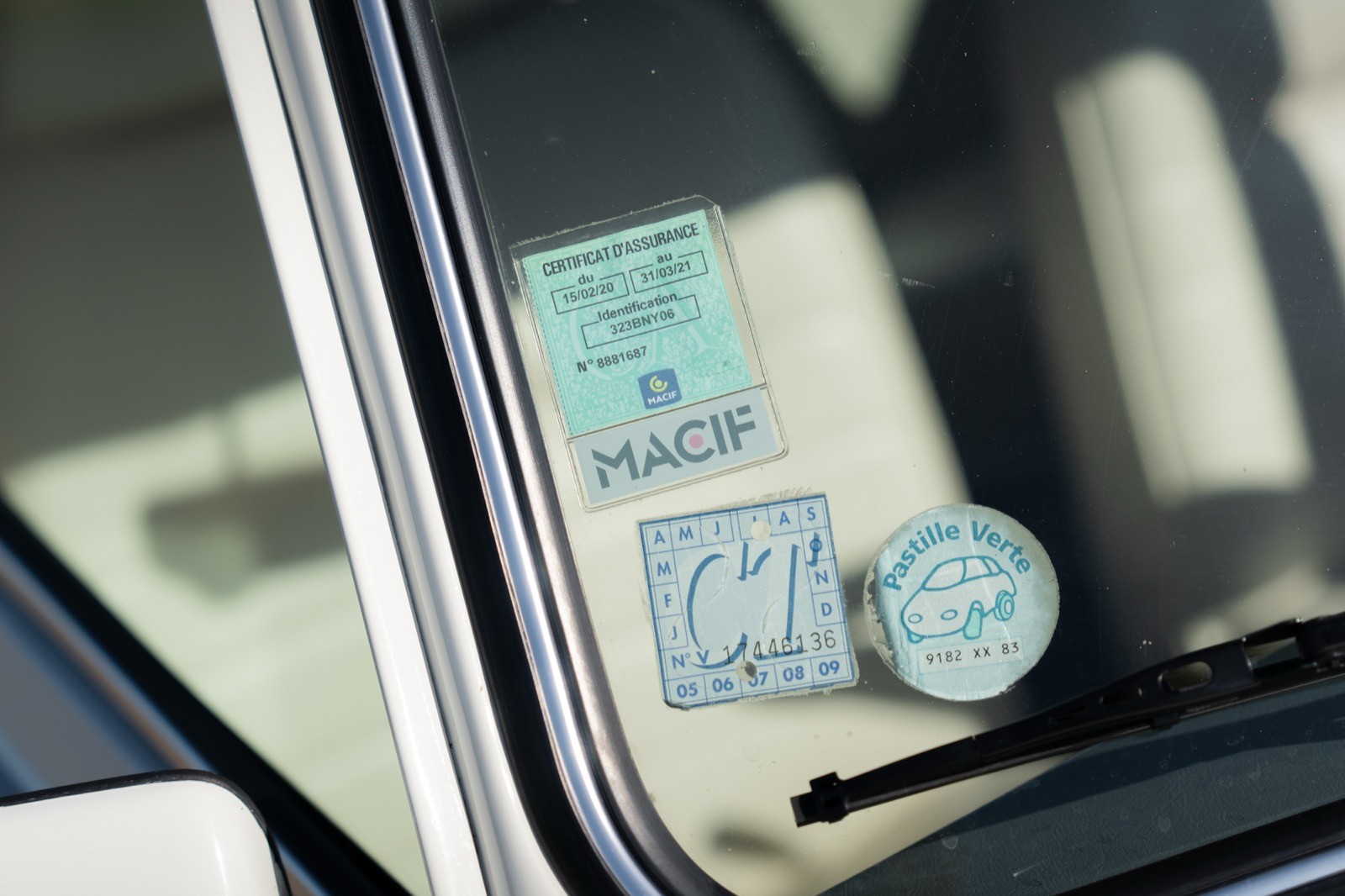 Close-up of a car's interior showing a dashboard with stickers and a round object on the window.