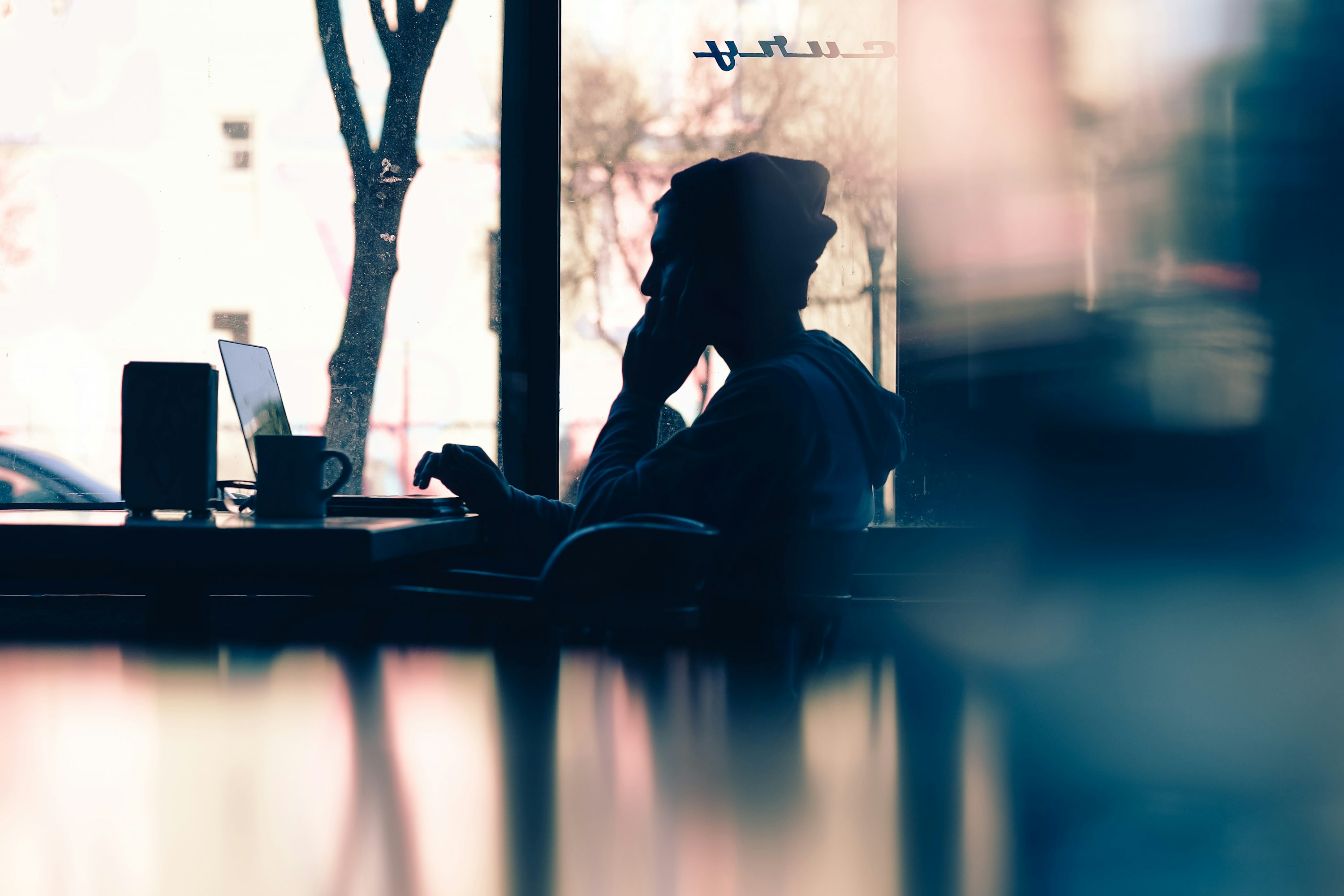 Person working on laptop in front of window with city view