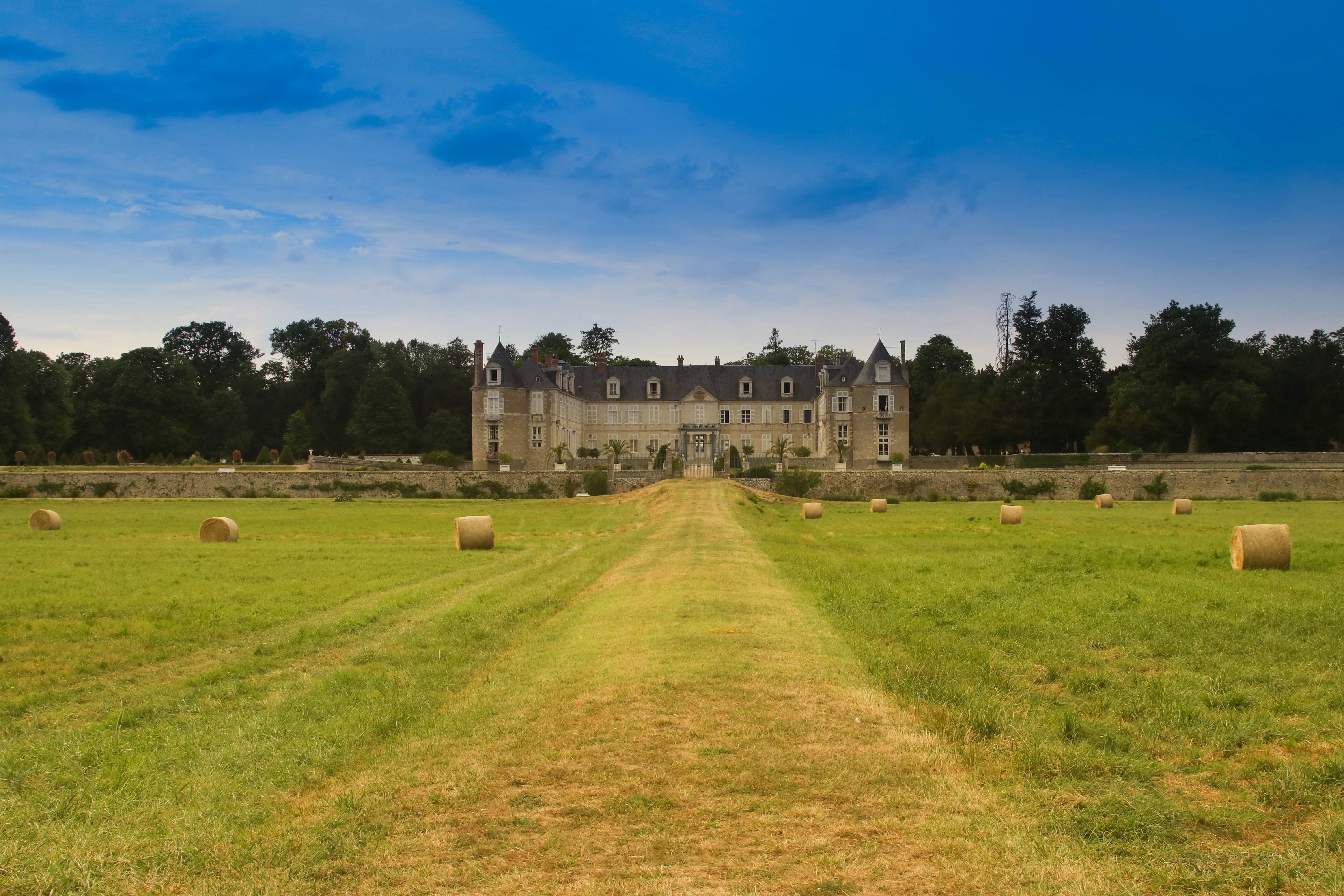 Two people lying on grass rolls in a royal garden around a traditional-style building.