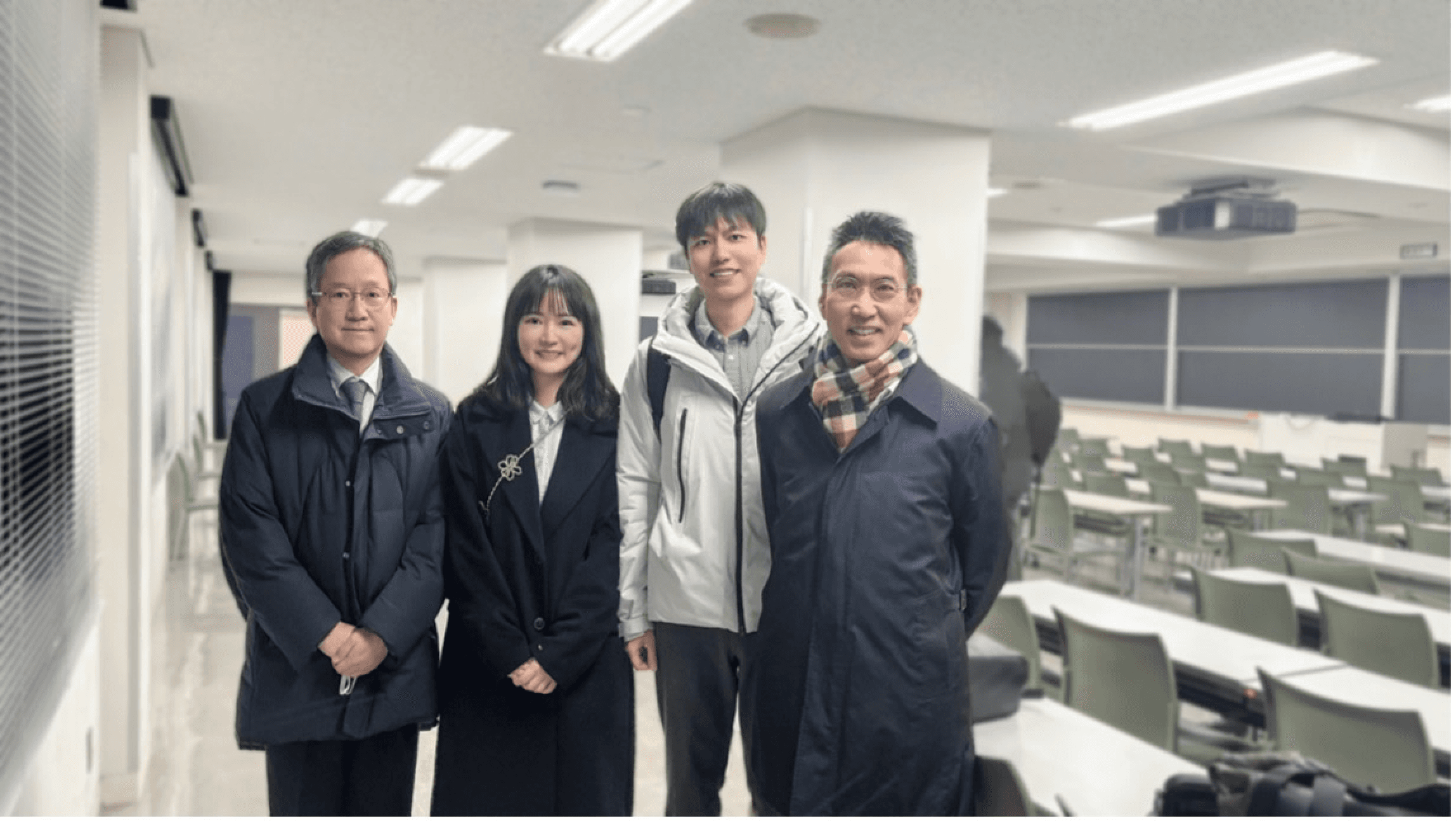 Group of professionals or researchers standing together in a classroom setting, smiling at camera