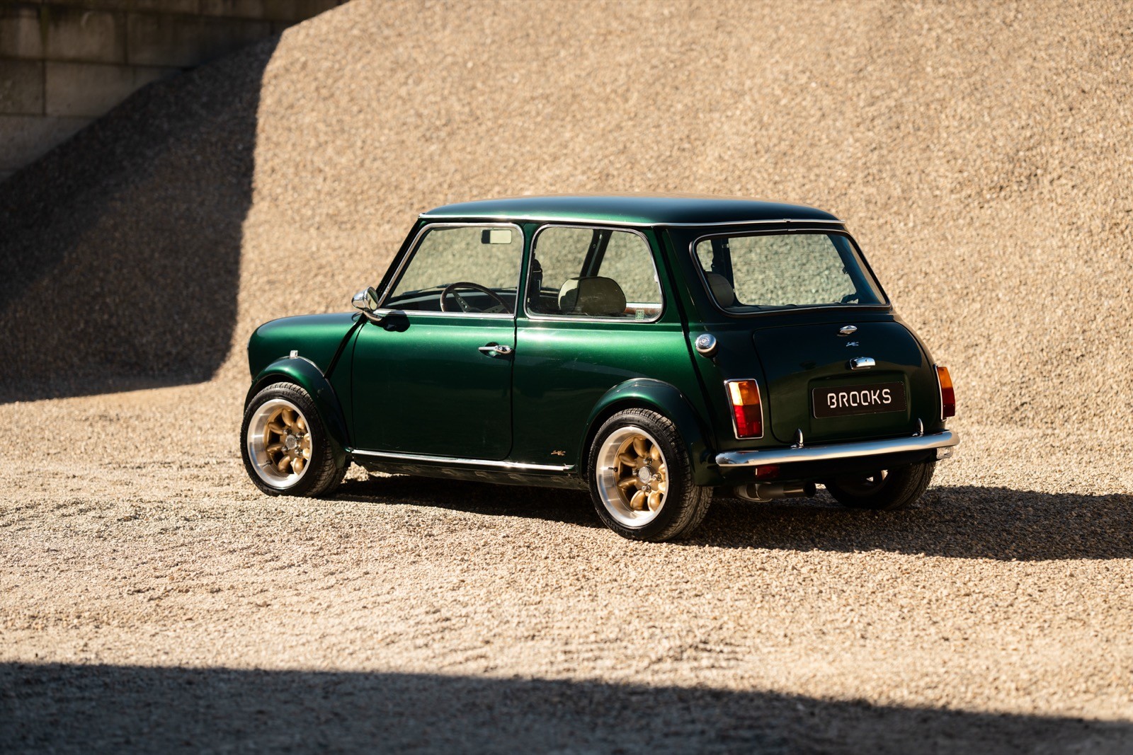 A small, green and black vehicle parked on a sandy surface, with a warm sunset lighting the scene.