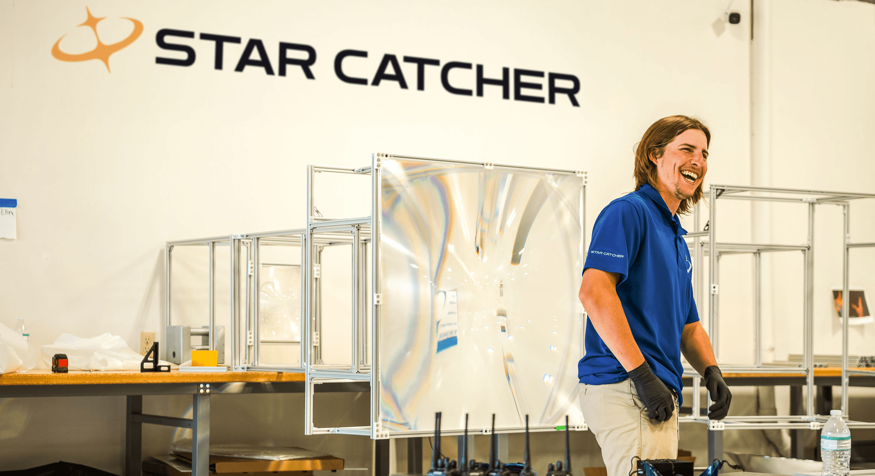 Star Catcher engineer laughing with fresnel lens hardware in background at manufacturing facility