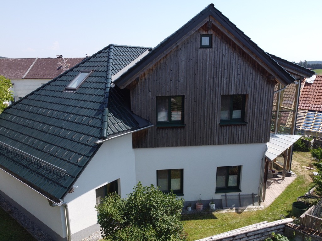 Gartenseite von Haus am Licht mit Holzfassade und Wintergarten