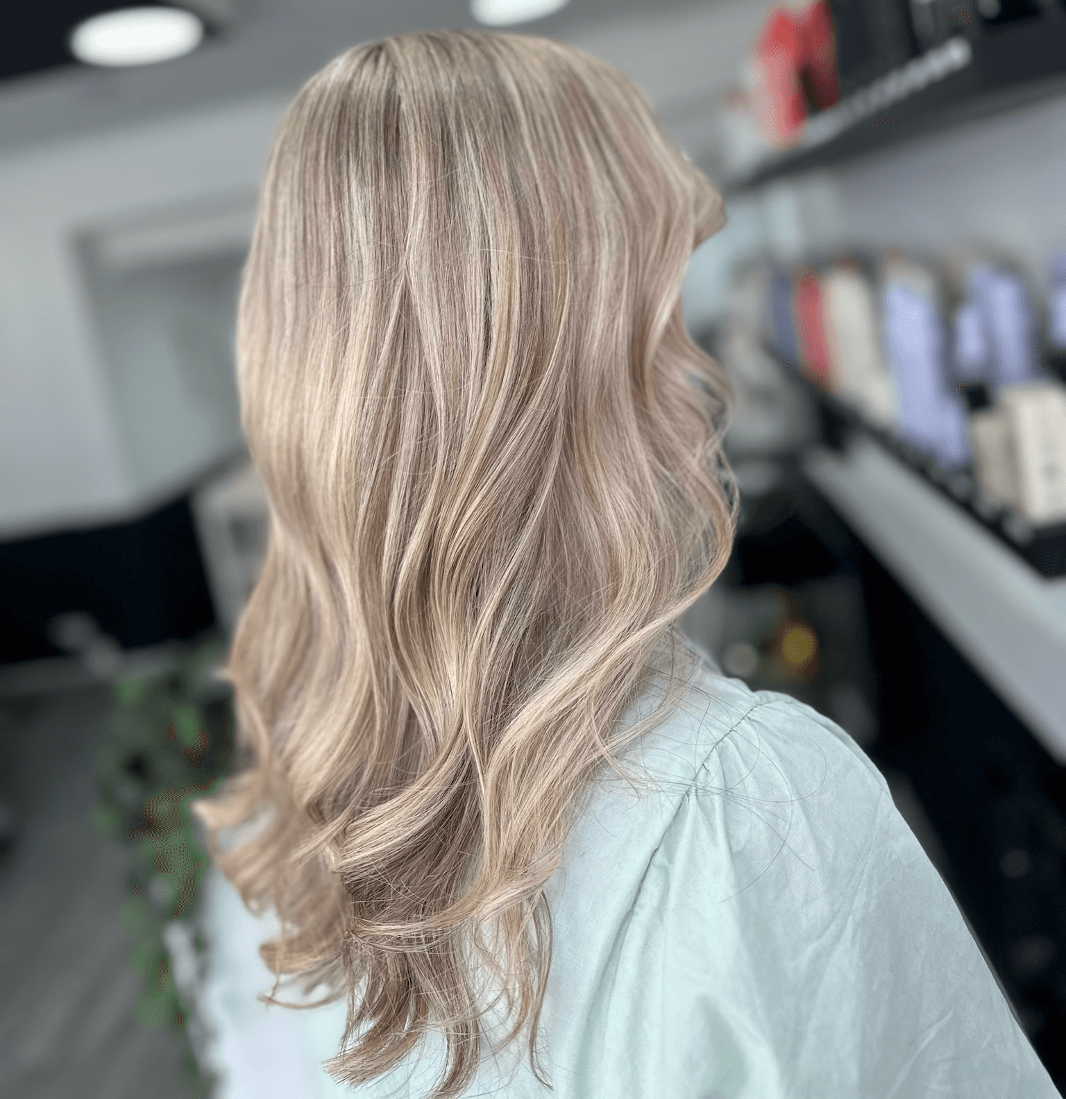 Woman with long wavy blonde hair with purpler highlights at Inspire Studio Salon