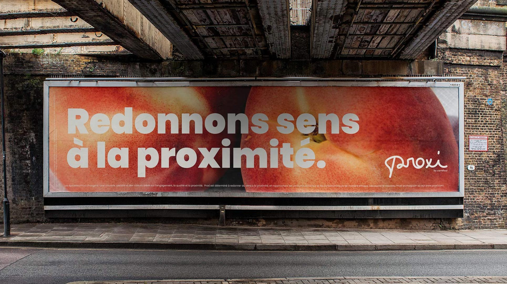 Affiche publicitaire urbaine sous un pont. Redonnons sens à la proximité sur des pêches en gros plan.
