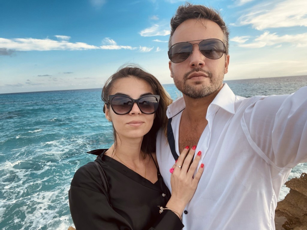 A close-up of two people holding hands, one wearing a denim jacket. The background is softly blurred, suggesting a tender, intimate moment in warm light.