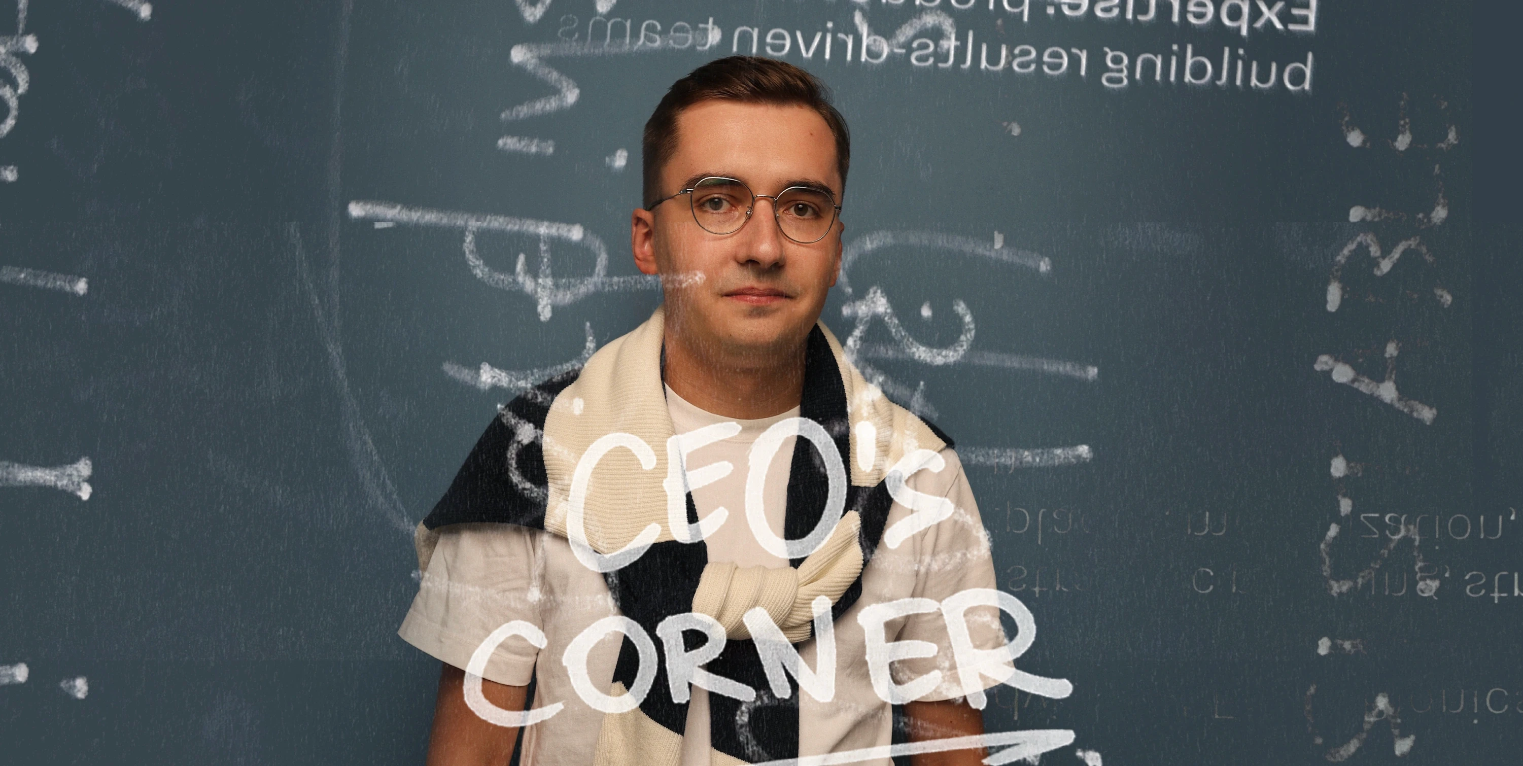 A portrait of a man standing in front of a dark background with mathematical and technical writing in chalk. He is wearing glasses, a light shirt, and a sweater draped over his shoulders. Overlayed in bold, handwritten-style text is "CEO's Corner," giving the image a creative and intellectual feel, as if he's in a workspace or a brainstorming session.