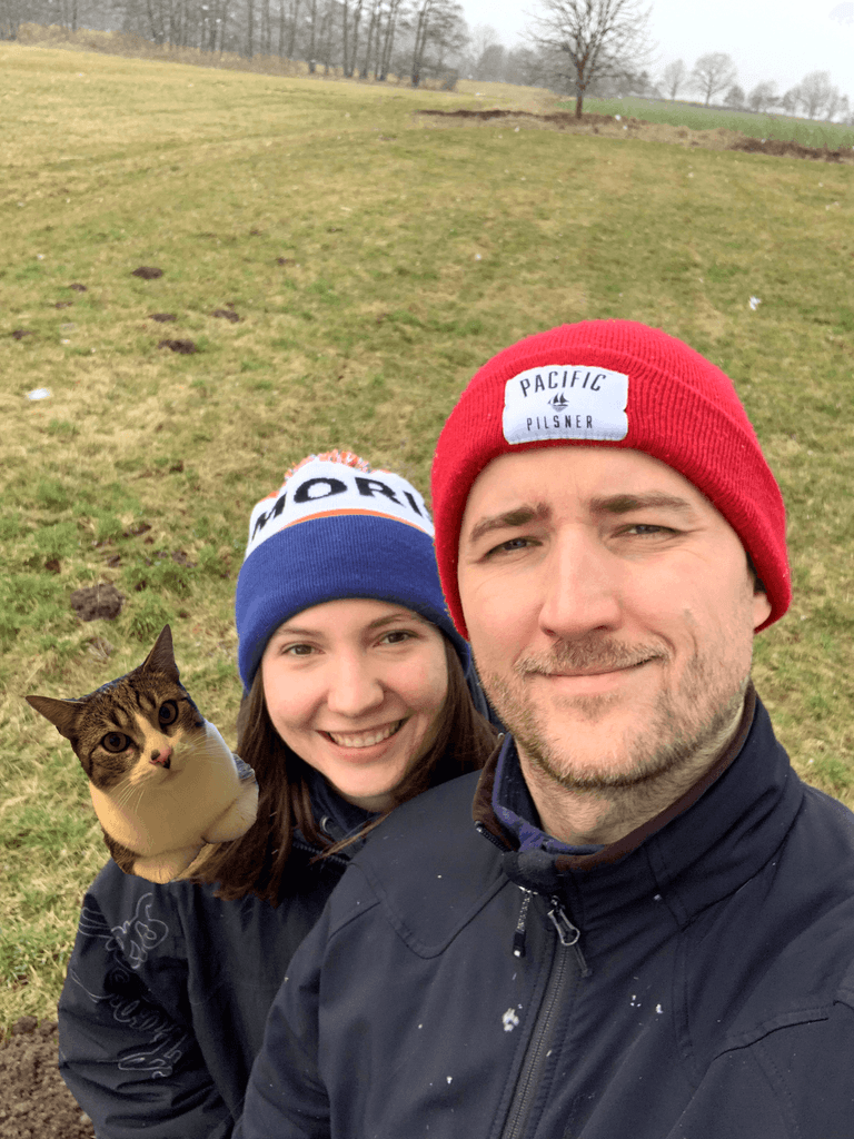 Couple sitting on a grassy hill overlooking a mountain valley.