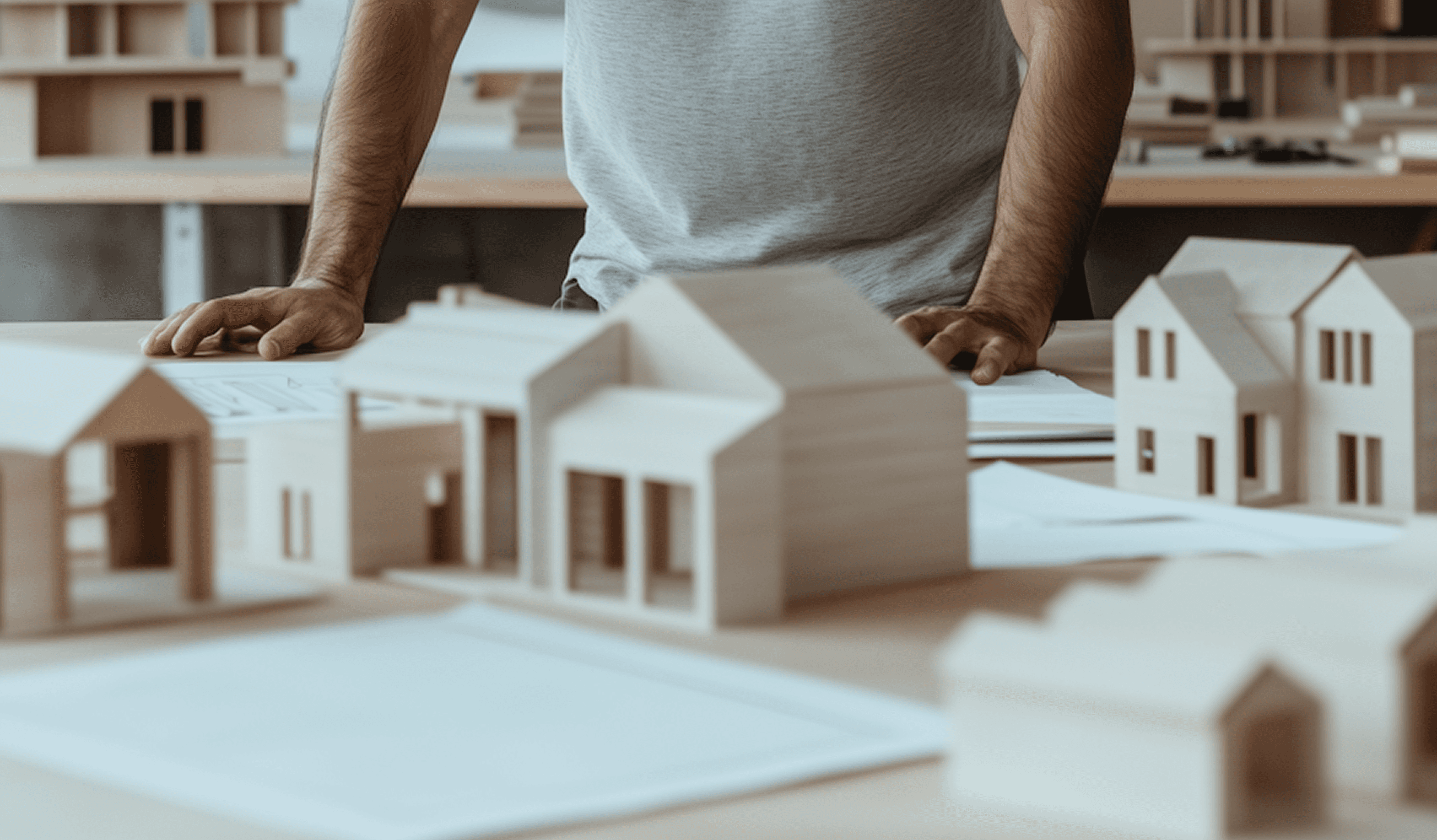 A man is focused on constructing a detailed model of a house at a workbench.