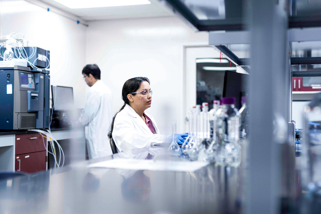 SteriMax scientists in lab coats and safety glasses working at a computer station in a laboratory.