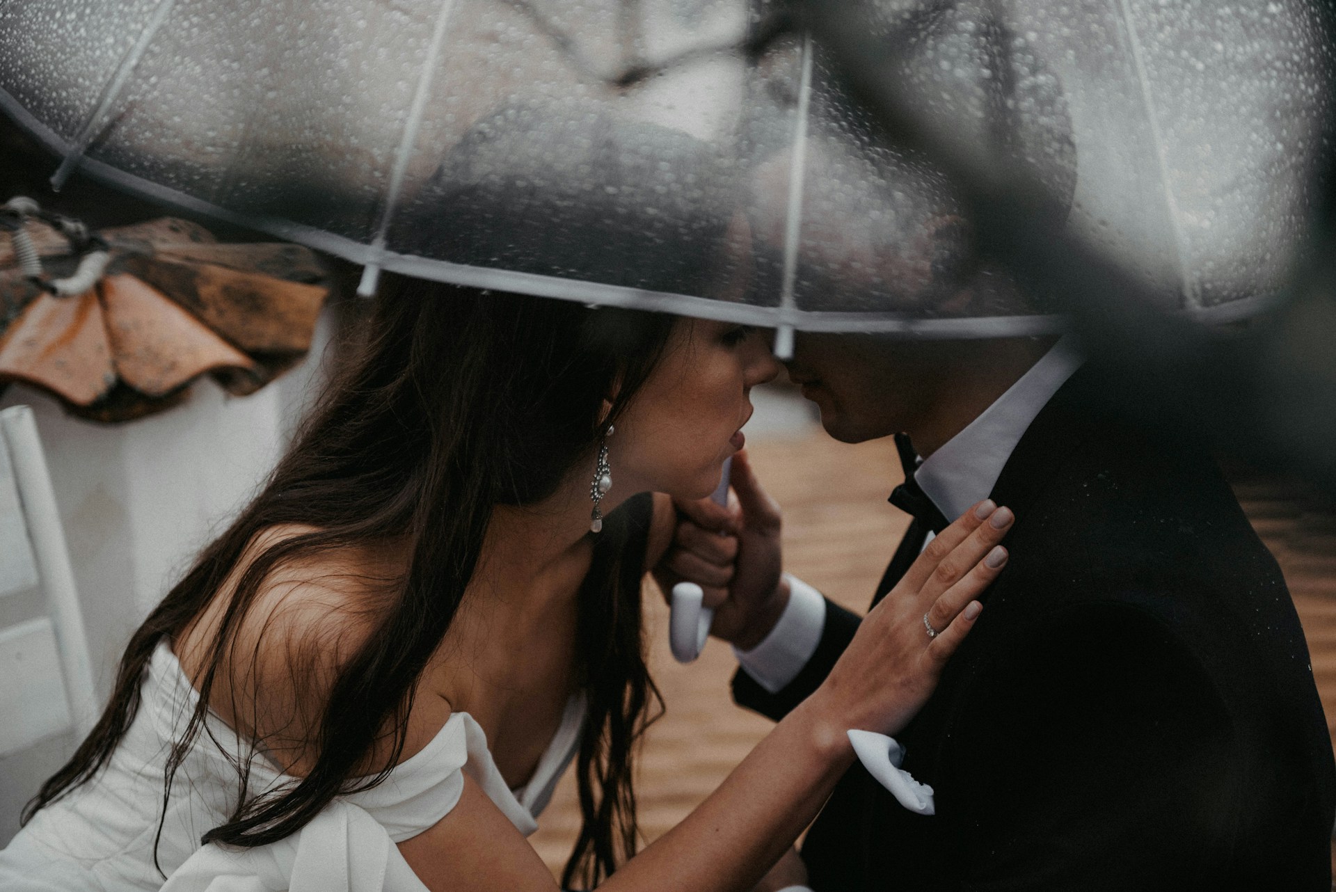 bride and groom under umbrella in the rain