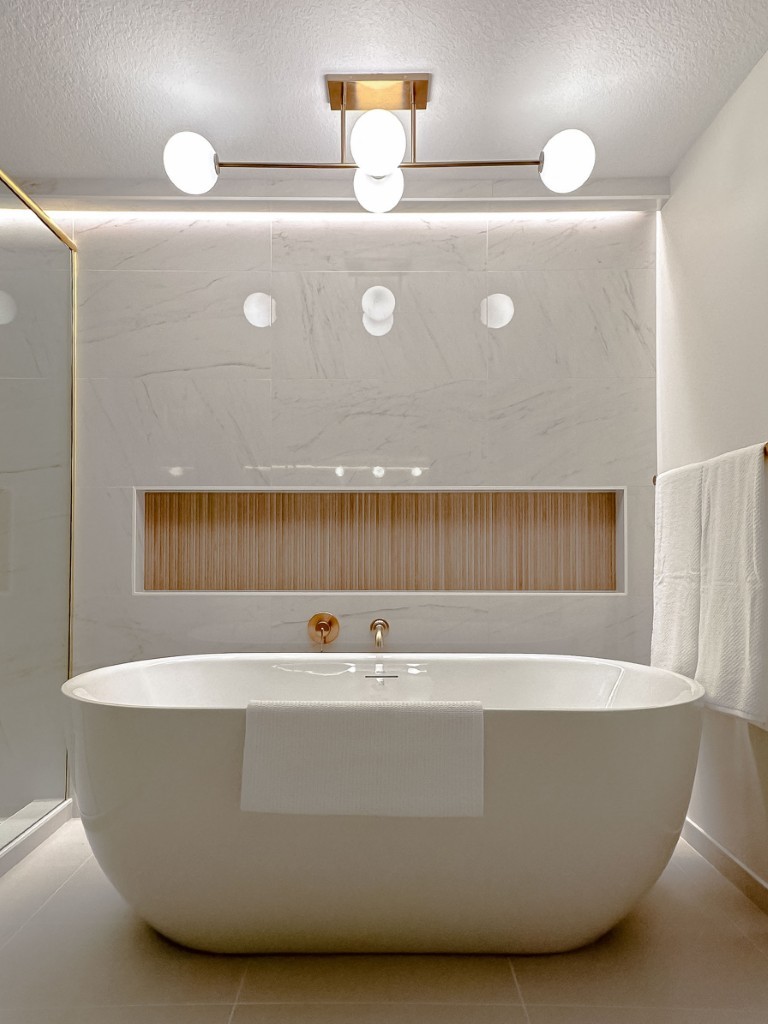 Image of Luxurious freestanding tub in modern primary ensuites bathroom design by KHD Homes with elegant lighting fixtures.