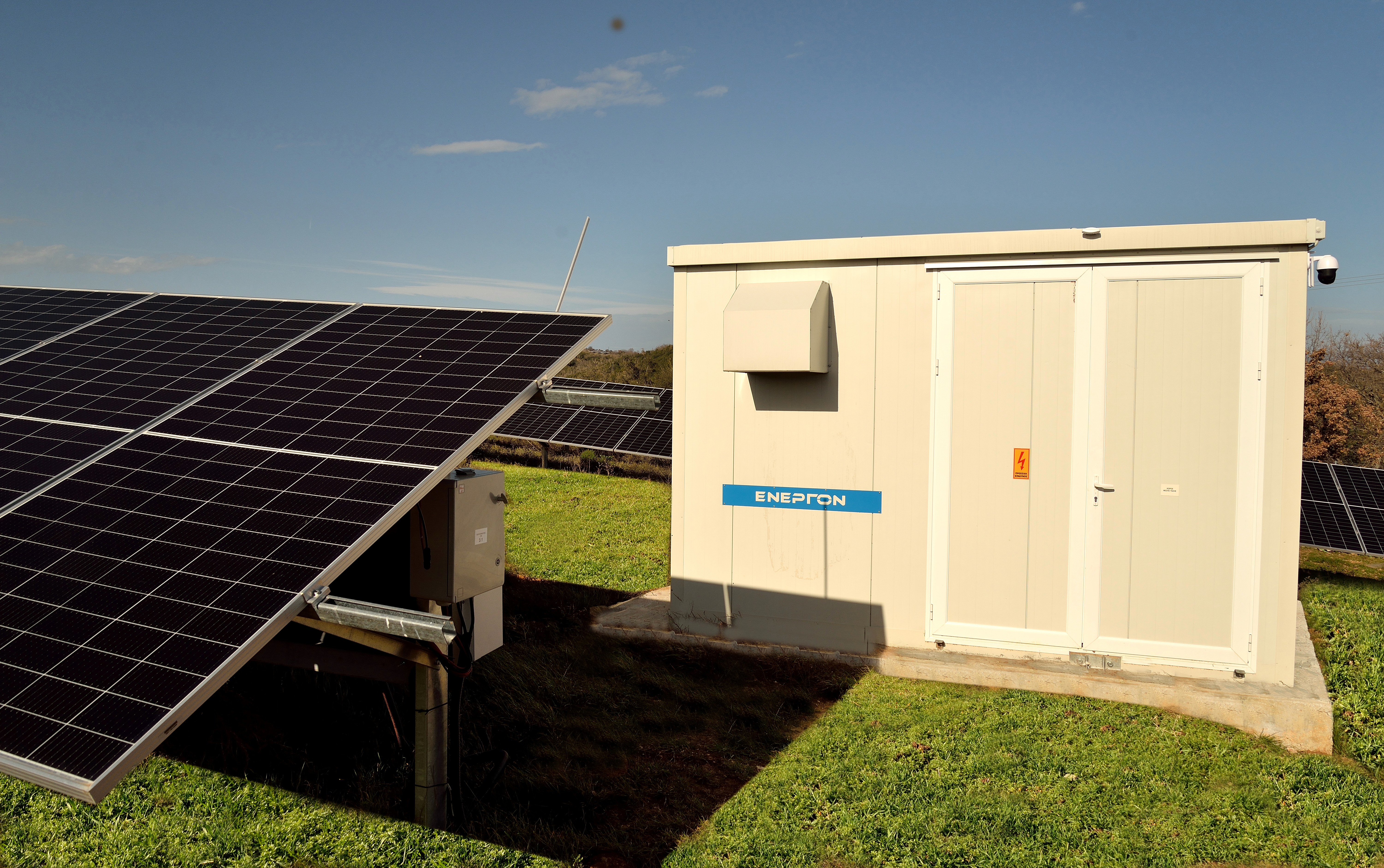 Electrical inverter station positioned next to ground-mounted photovoltaic panels in solar installation