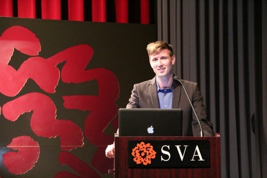 a man giving a speech from a stand in the "designer as" thesis presentation