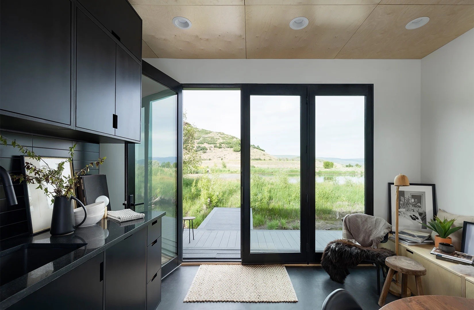 Modular home living room with large windows overlooking a large yard.