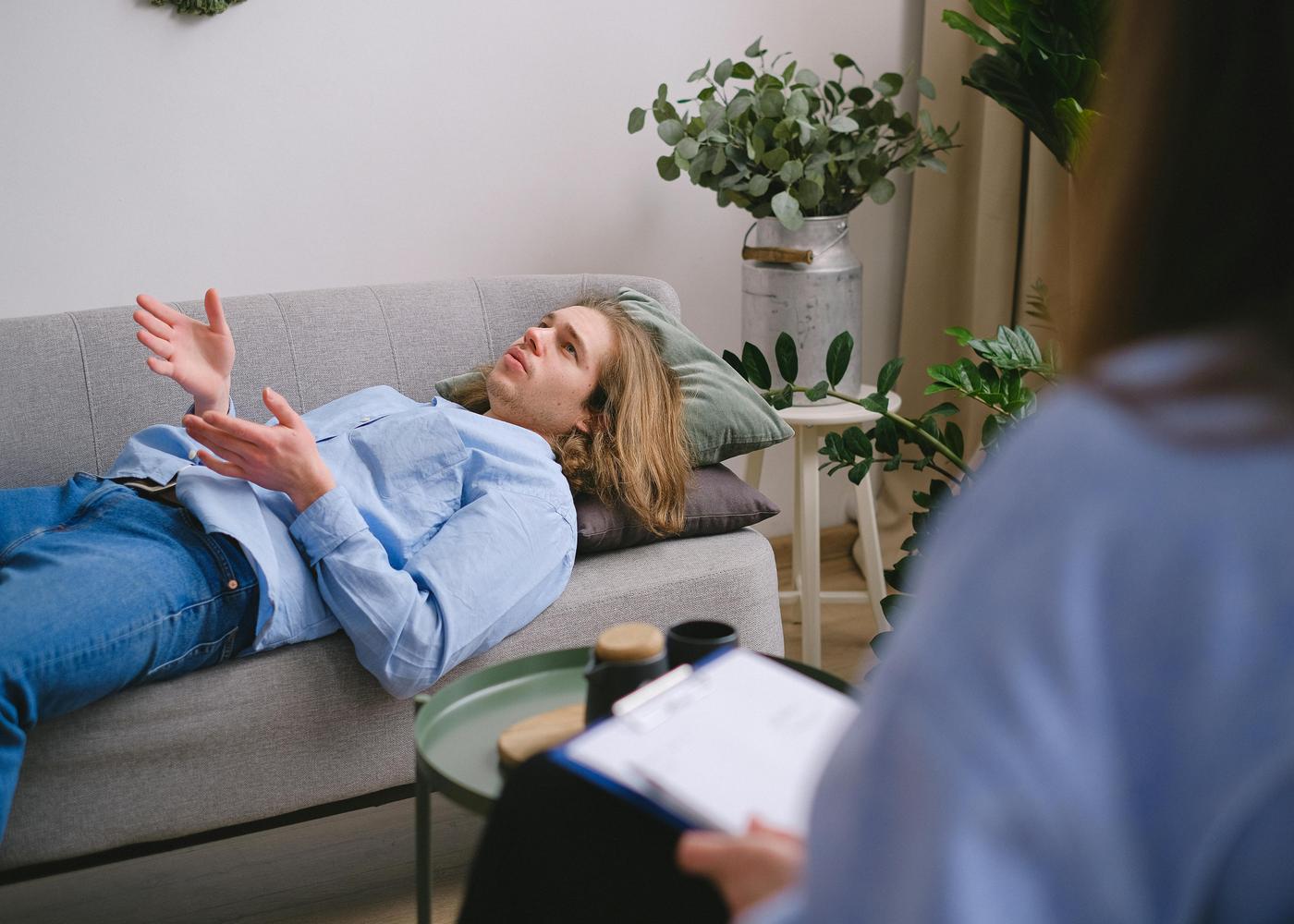 CBT therapy session with man lying on a couch and doctor taking questions