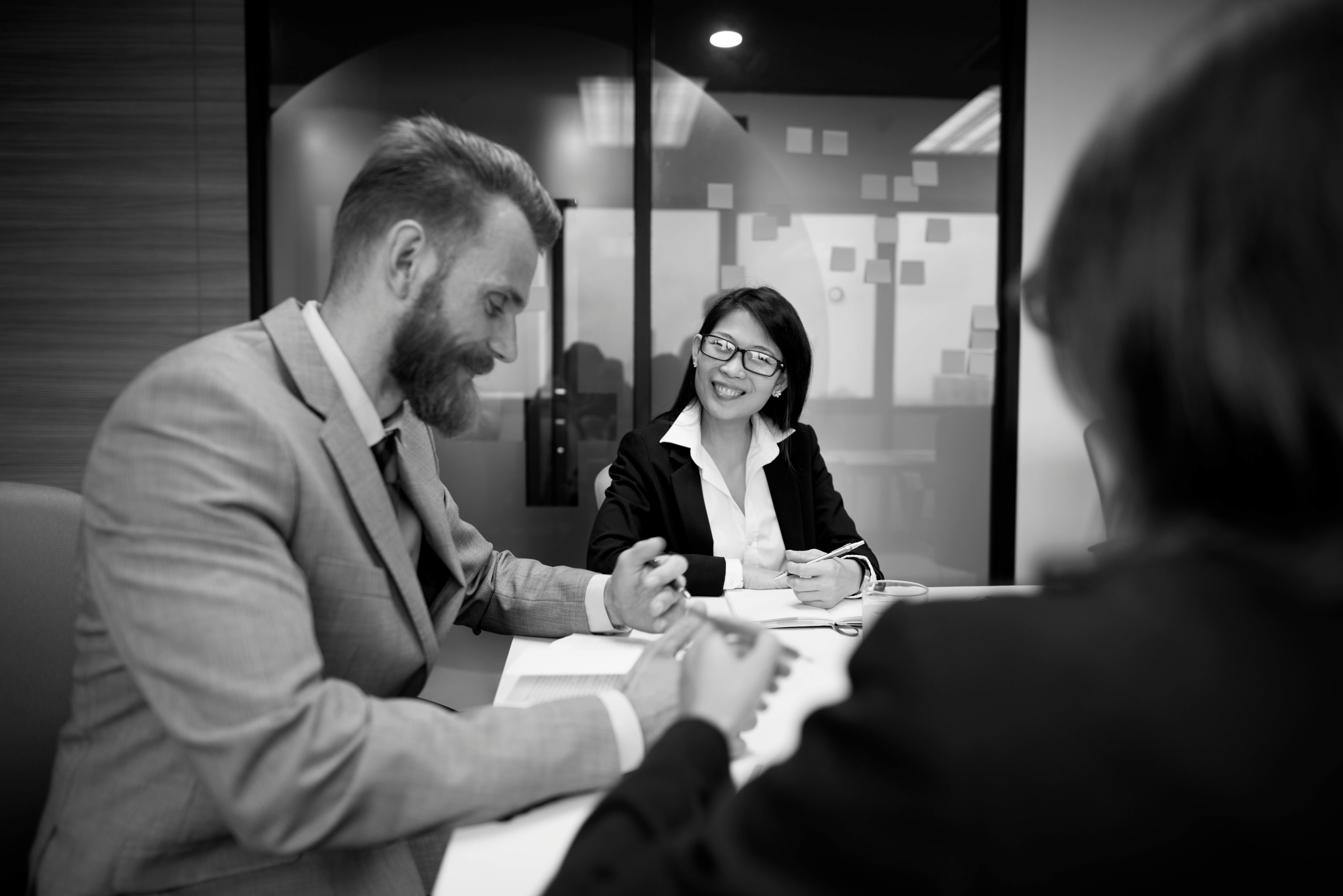 Three business professionals in conversation in meeting room