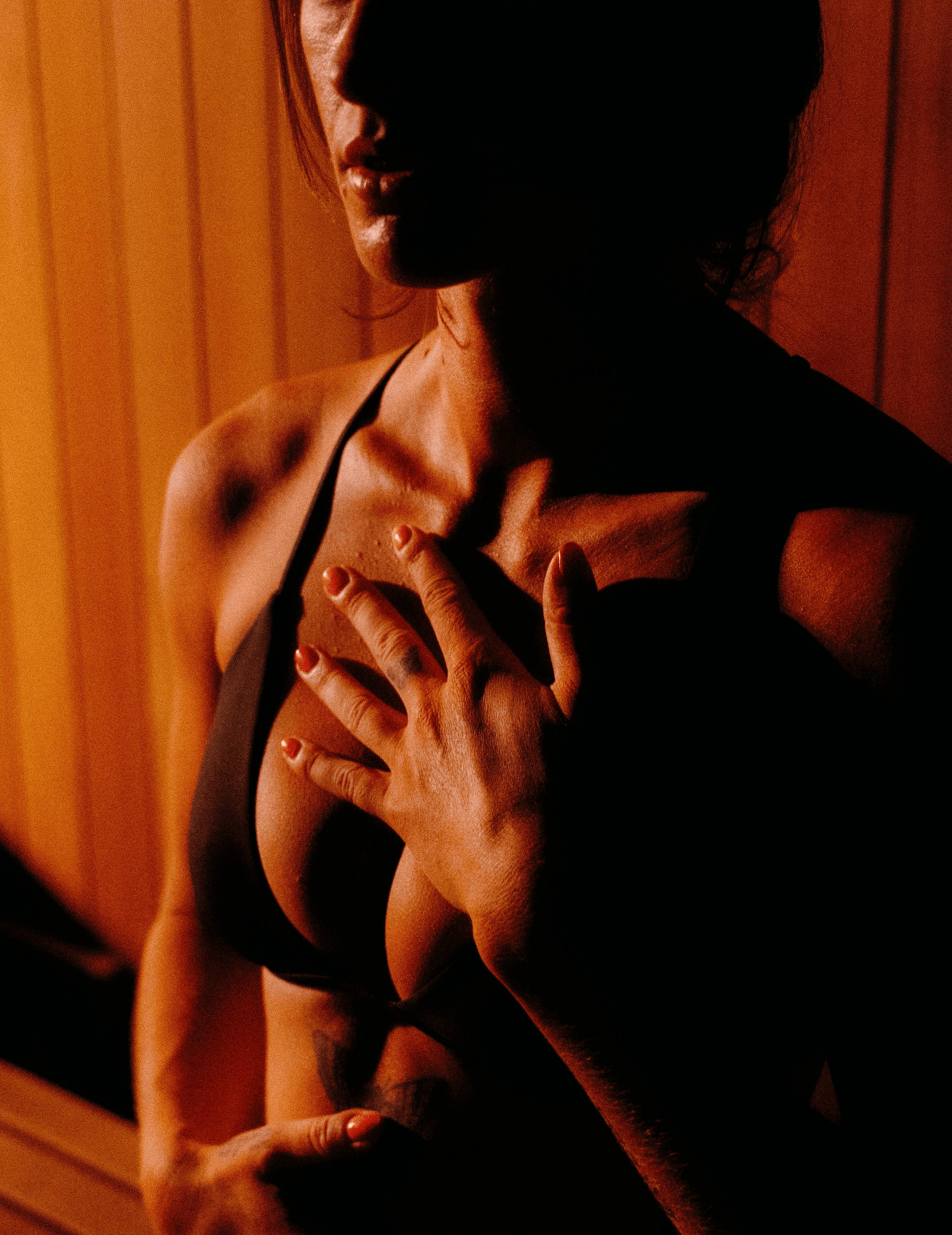 Person seated inside a warm cedar sauna, hands resting gently, embodying stillness and presence in traditional sauna practice