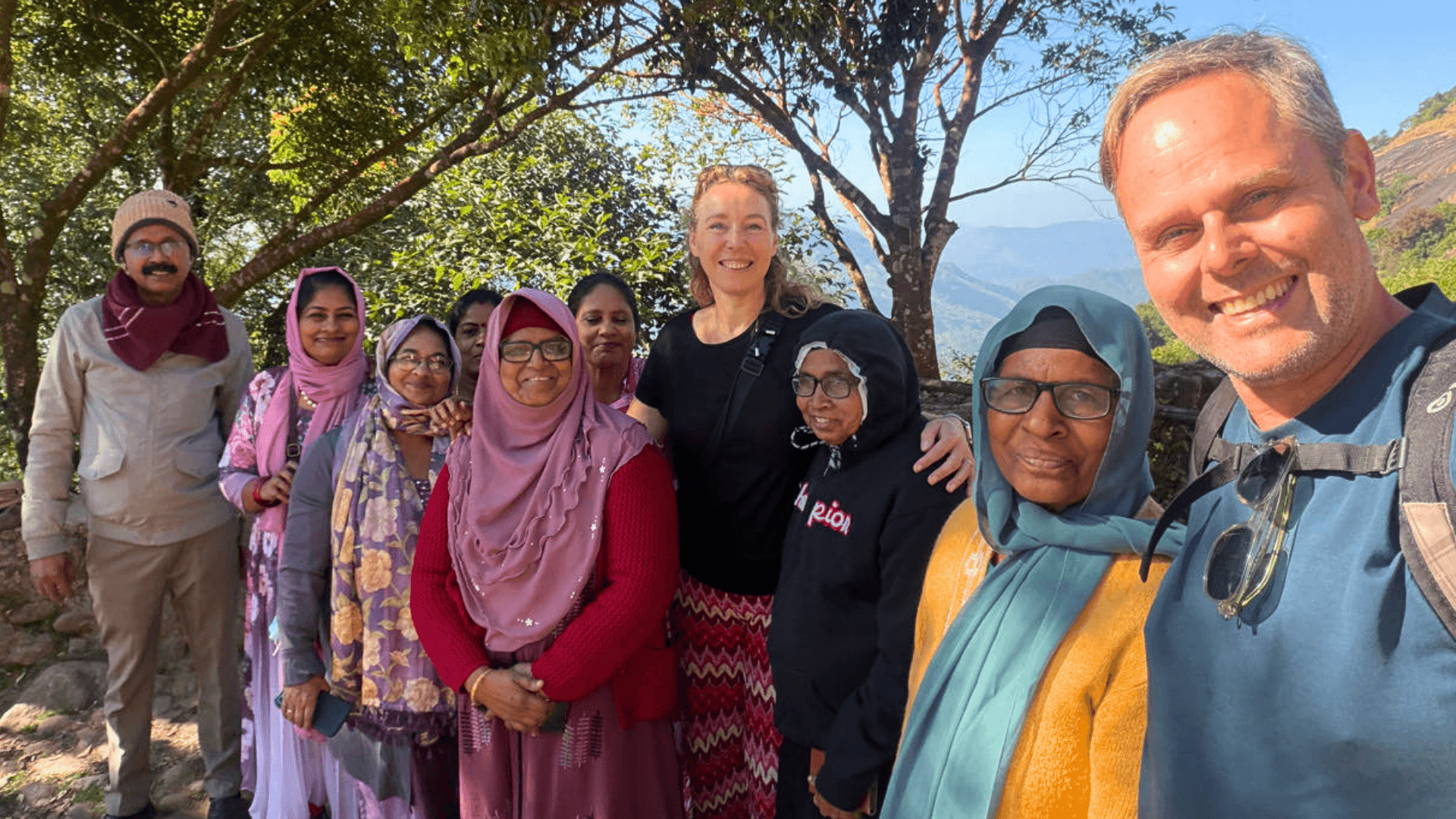 Traveling couple exploring an off-the-beaten-path village in India, warmly welcomed by surprised locals, creating authentic memories through Planout's local travel recommendations.