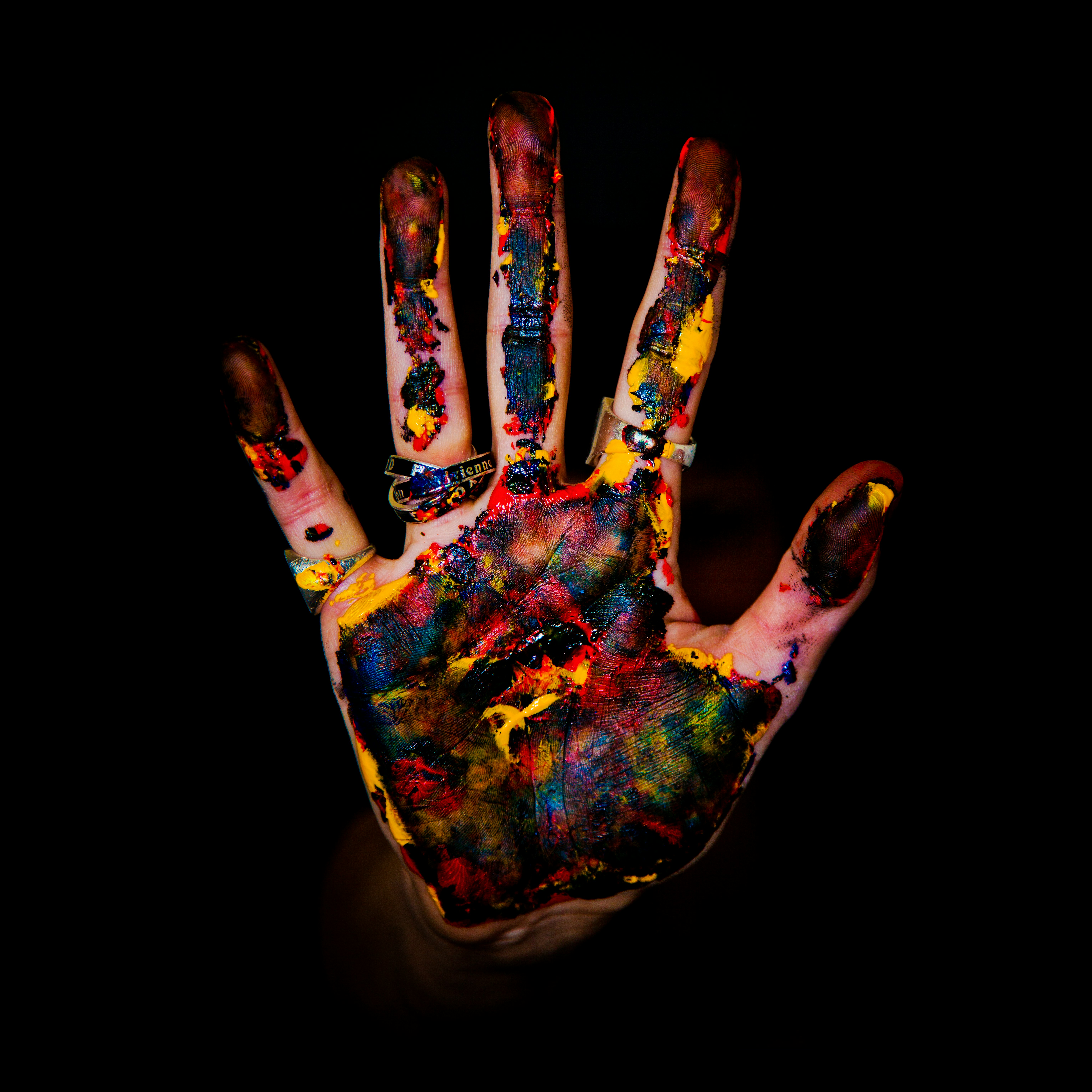 A hand with palm facing forward covered in paint.