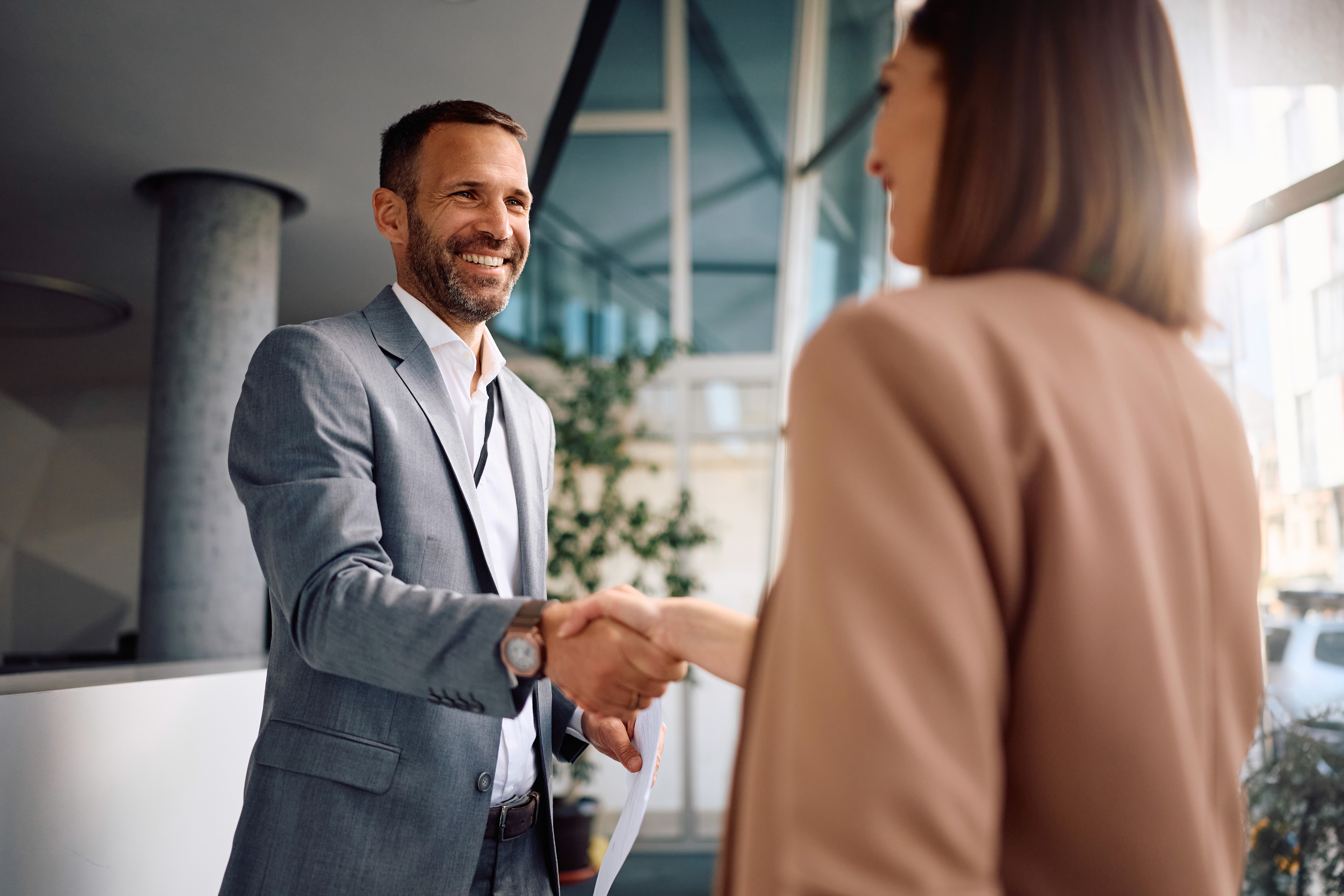 Mulher jovem segurando papéis e sorrindo, com um vestido azul