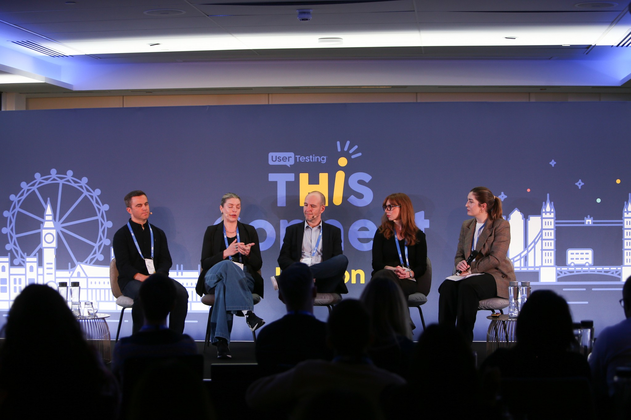 A panel event with 4 speakers sitting and a host. Samantha sits second from the left.
