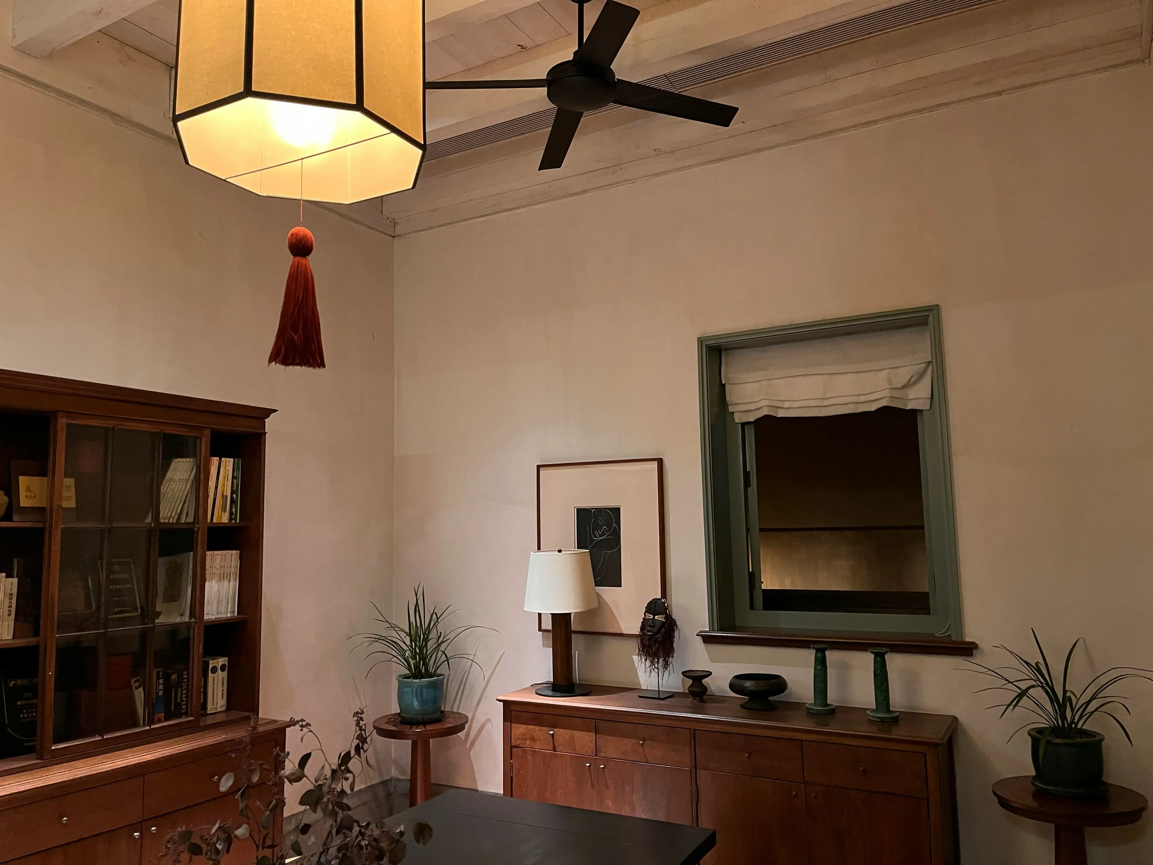 A room featuring a ceiling fan, a lamp, bookshelf, and other furniture.