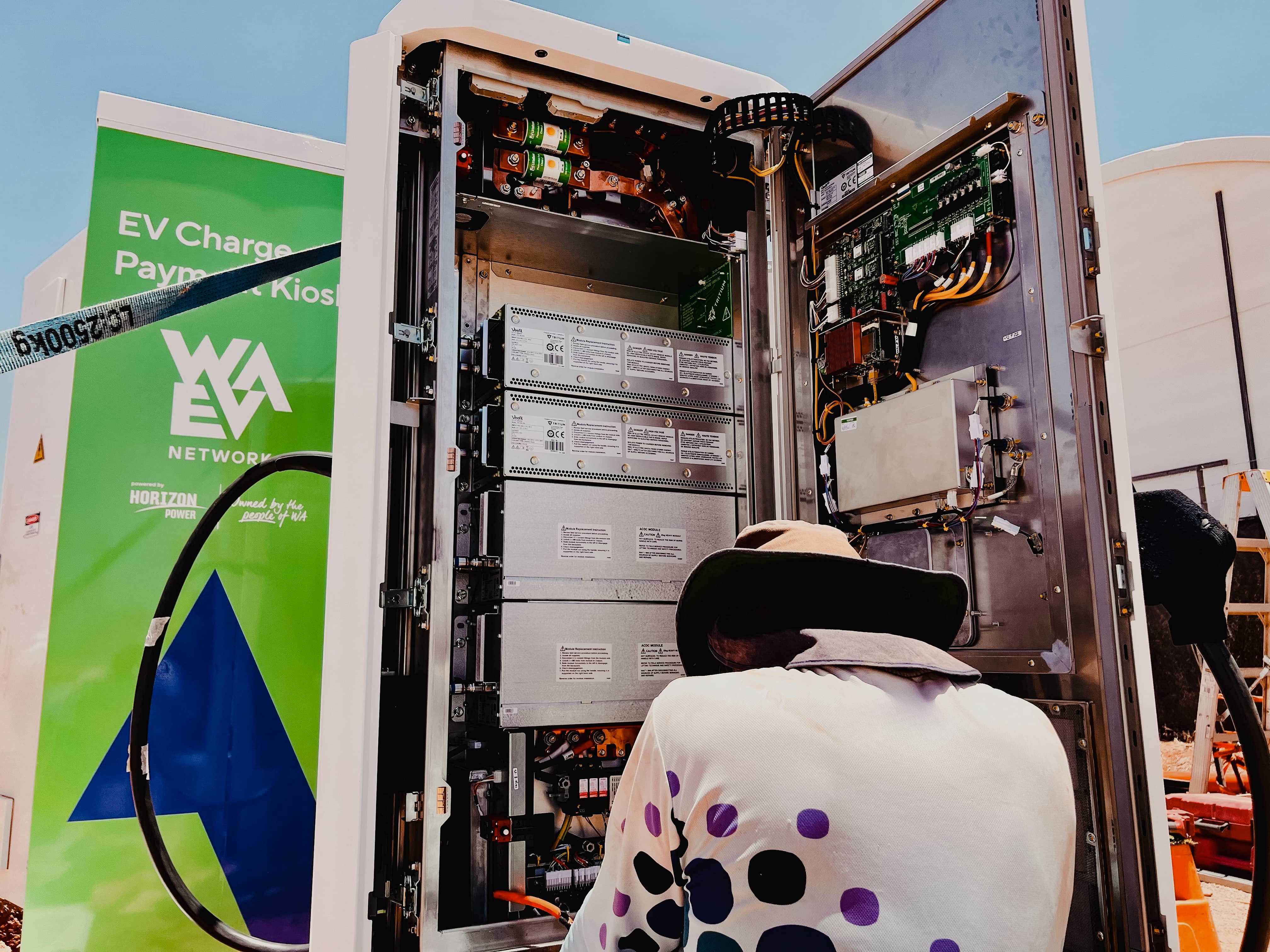 Powerhouse Renewables Group technician working on EV charging station electronics for WAVE Network, powered by Horizon Power