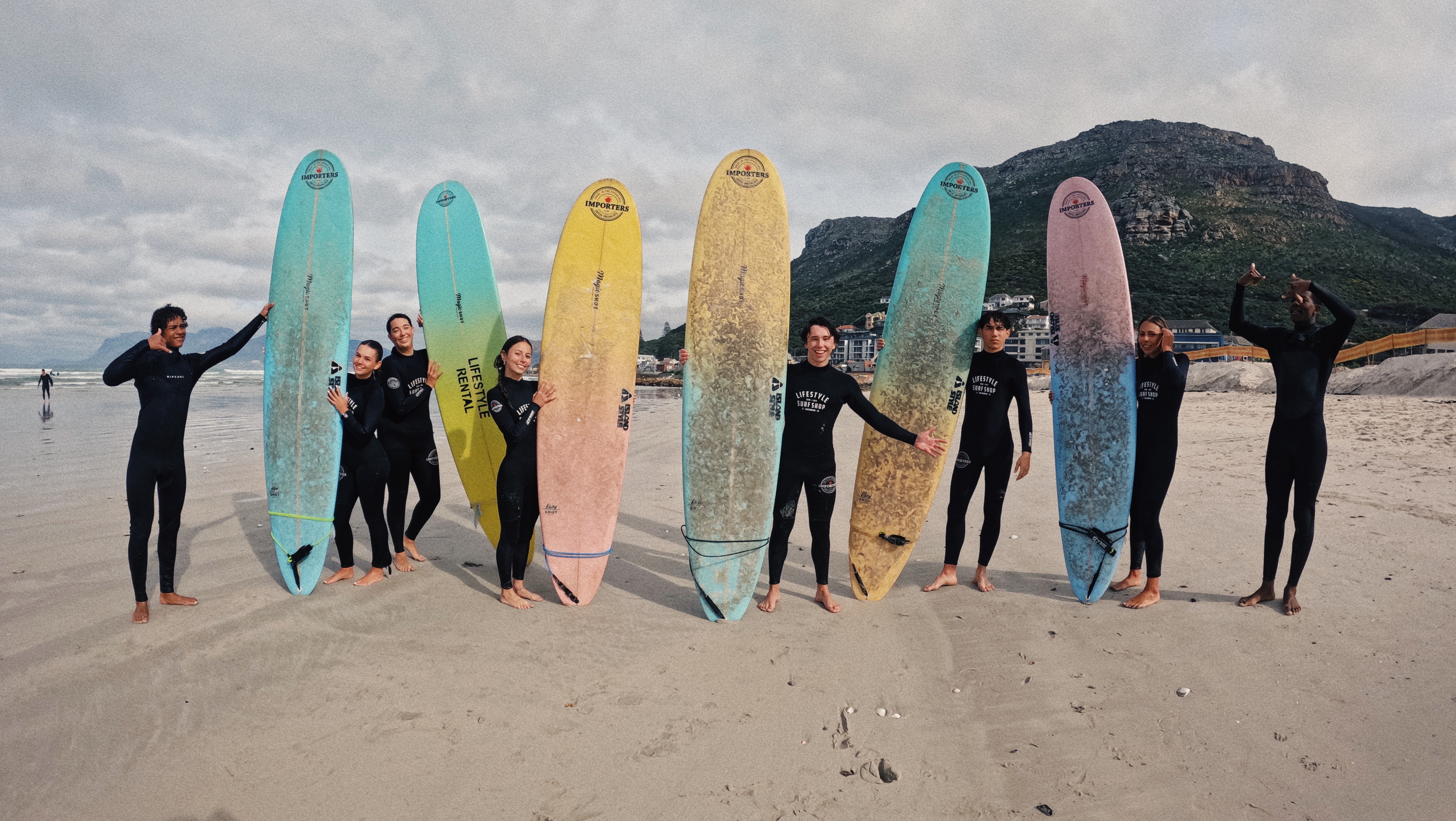 A group of beginner surfers having a fun experience during a surf camp in Cape Town at Muizenberg beach