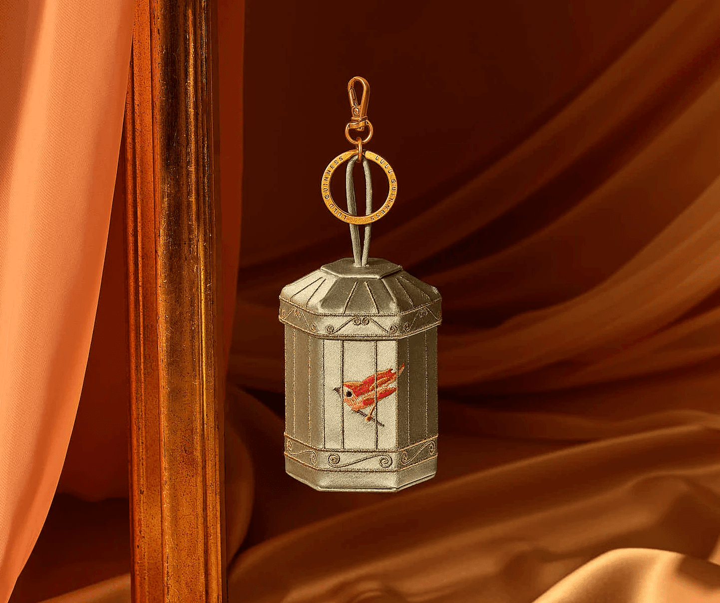 Elegant birdcage handbag with intricate design on orange fabric backdrop.