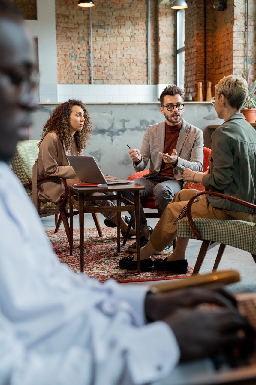 A group of four people engaged in a discussion while seated in a cozy, plant-filled setting.