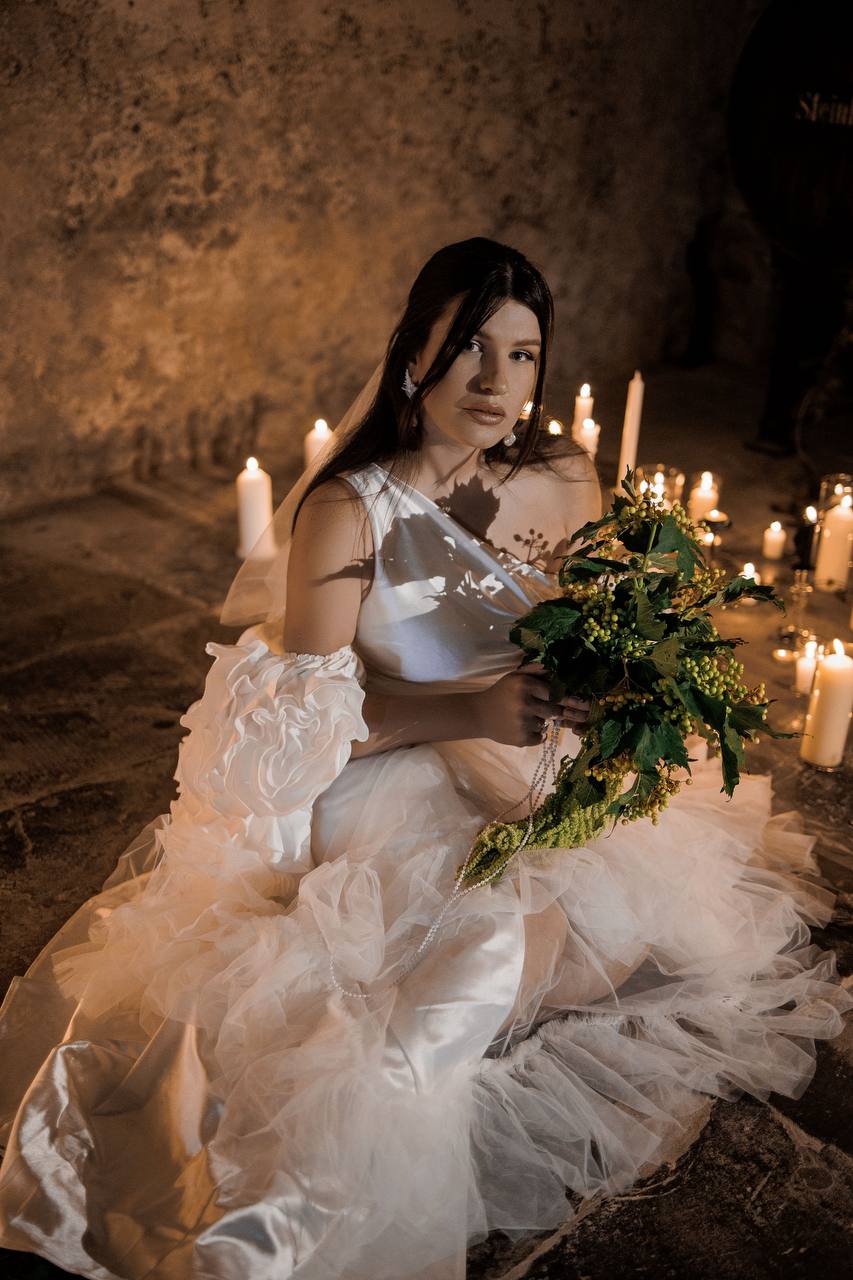Bride holding a floral bouquet in an intimate candlelit wedding setting