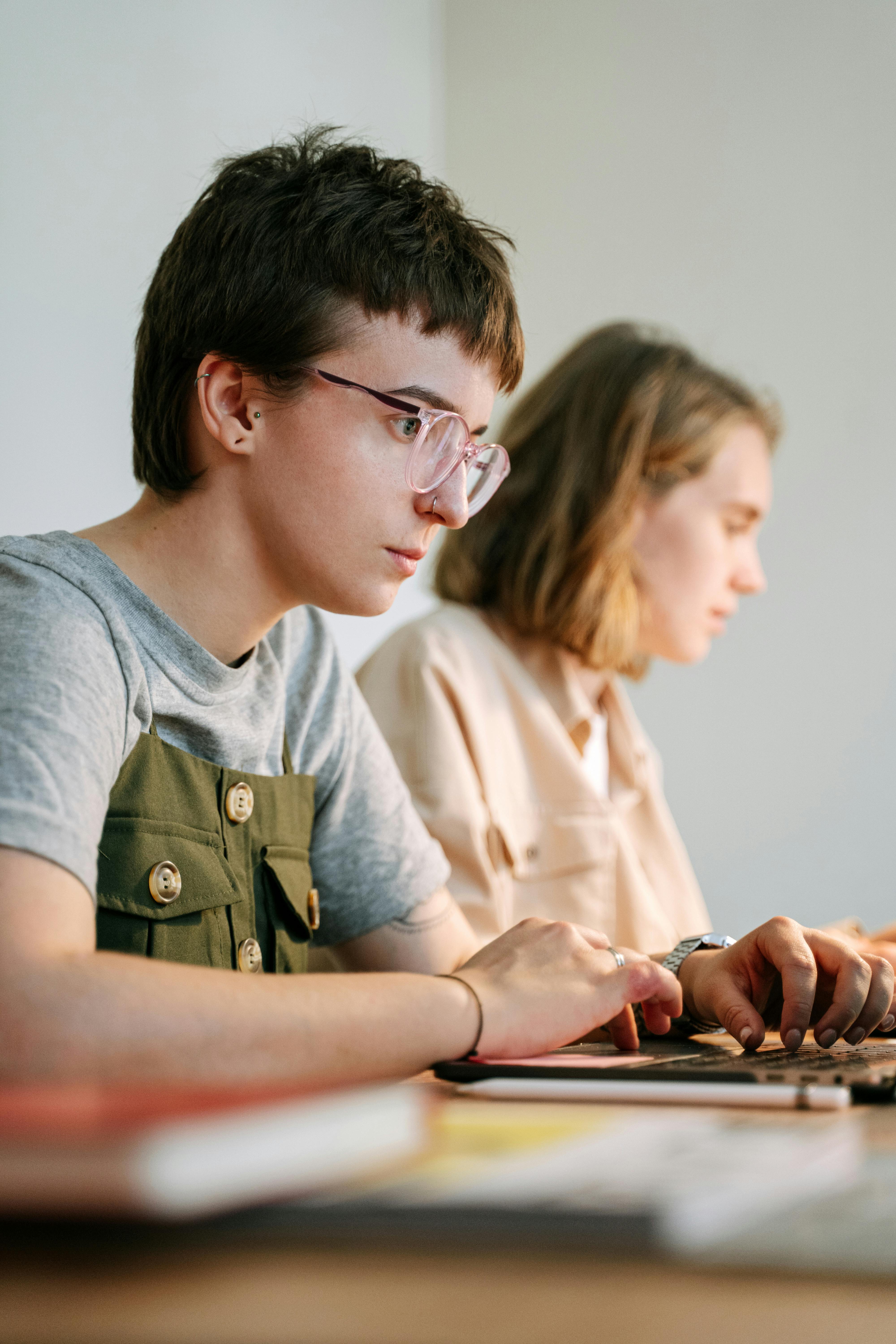 Due giovani che lavorano concentrati al computer in un ambiente informale, rappresentazione della Gen Z al lavoro tra focus e ricerca di condizioni eque.