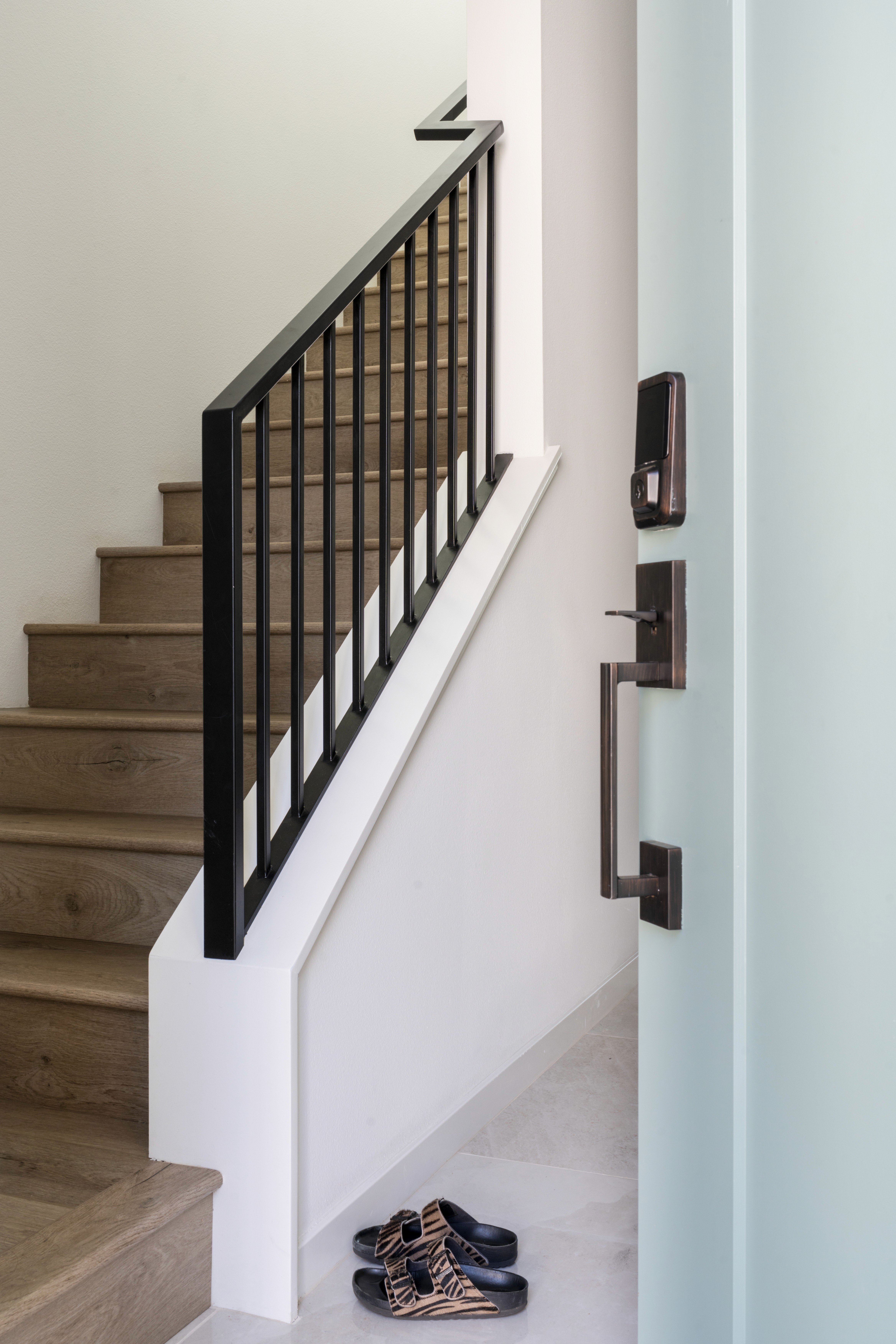 Stair case with white walls, black railings, and neutral wood steps by Jubilee Interiors in Arcadia, California