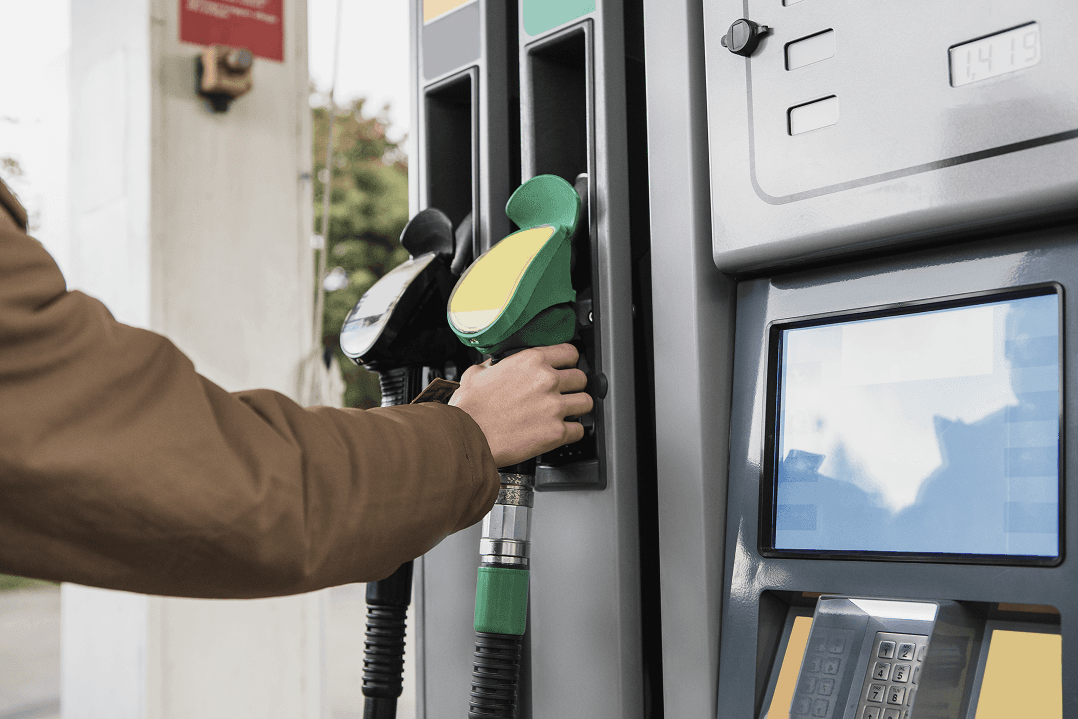 Șofer alimentând mașina cu combustibil la pompa din benzinărie, acțiune urmată de scanarea rapidă a bonului fiscal în aplicație