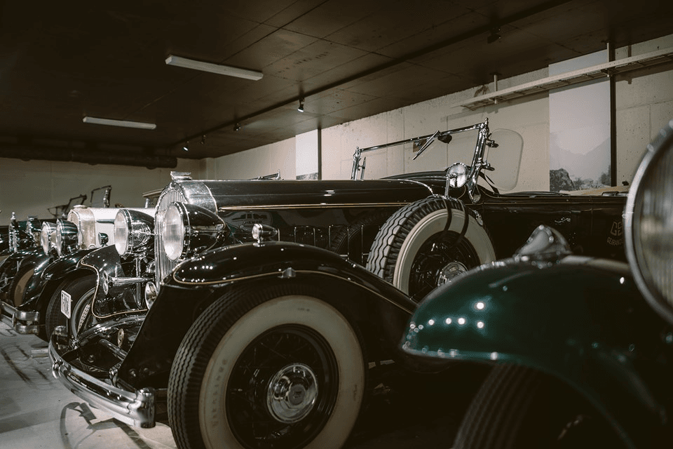 Vintage cars lined up in a dimly lit garage, showcasing their classic design and tires.