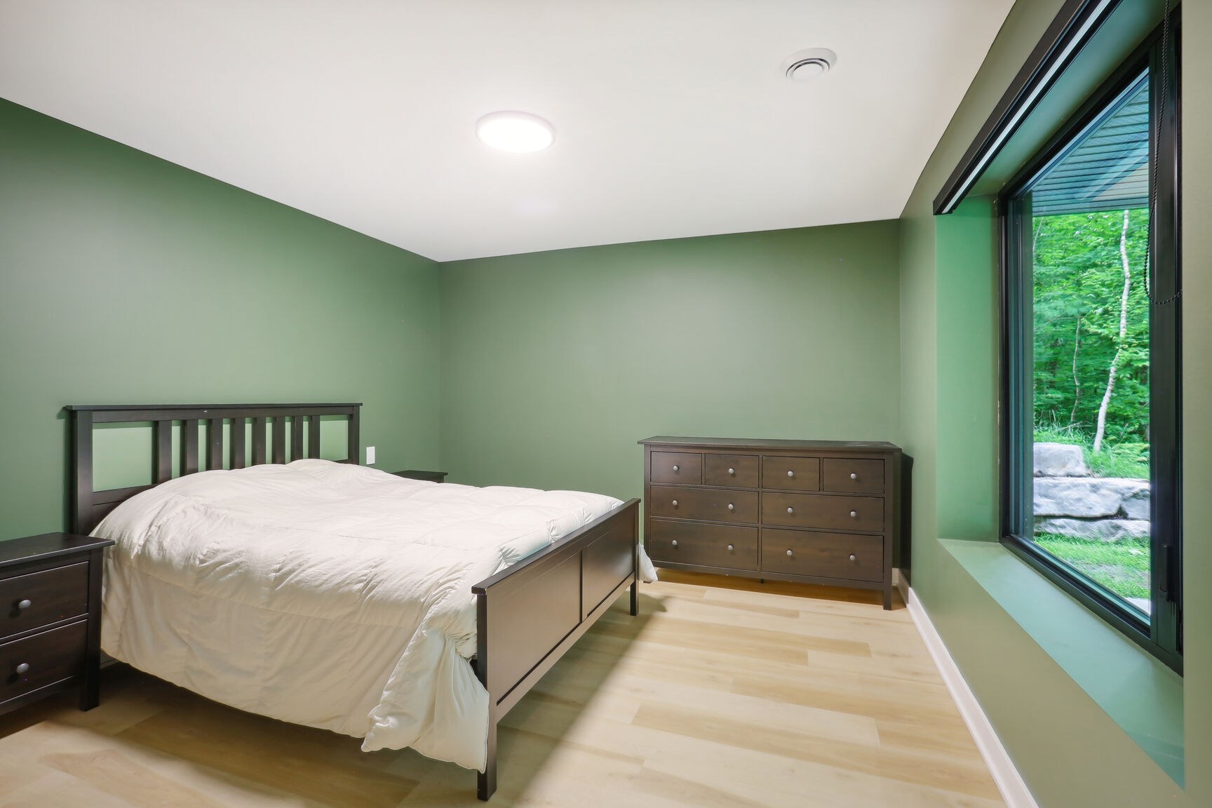 Chambre du niveau jardin, murs verts, grande fenêtre.